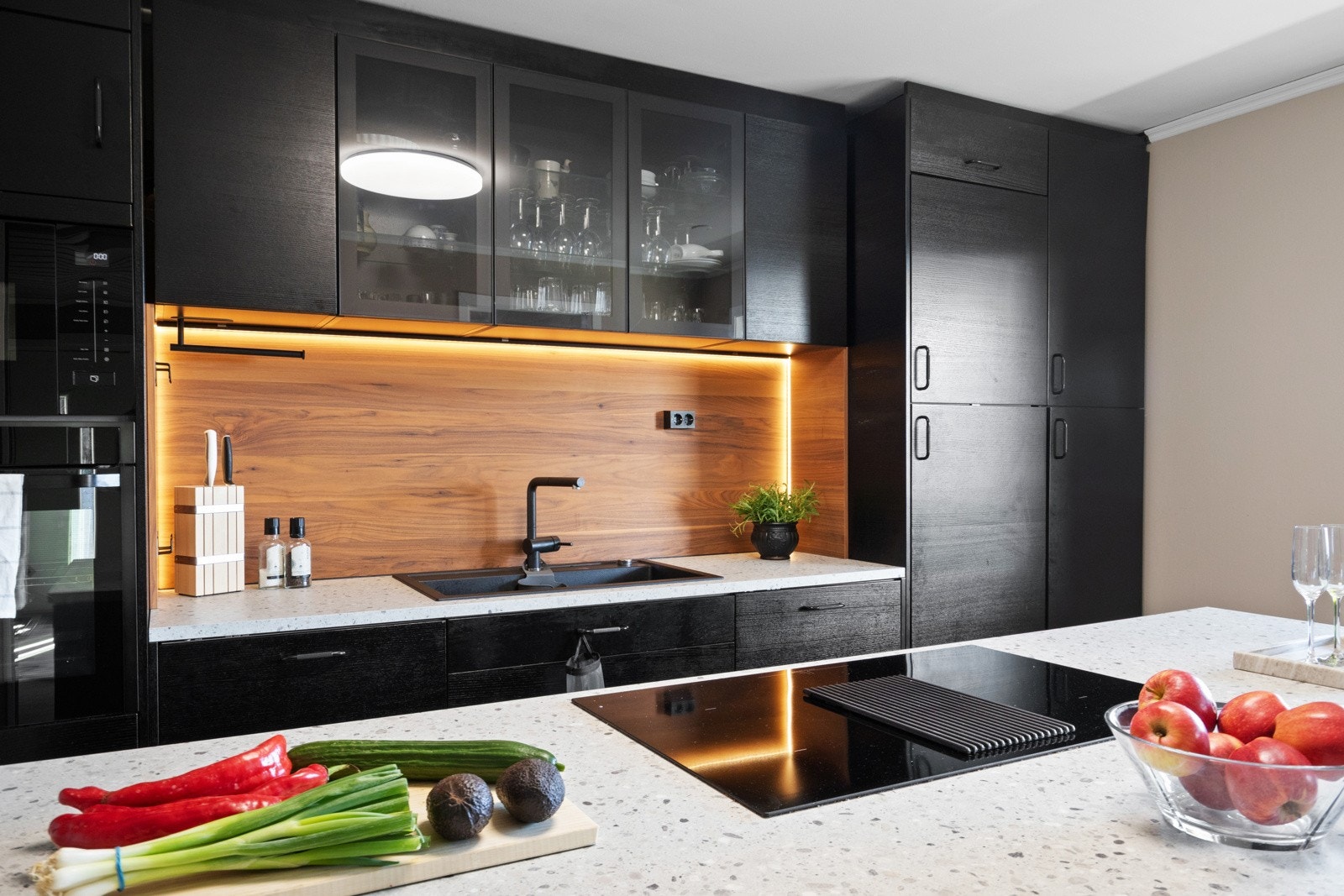 Innredningen har sorte, glatte fronter, vitrineskap og lys, mønstret benkeplate av laminat med stor oppvaskkum i sort utførelse. Galleribilde