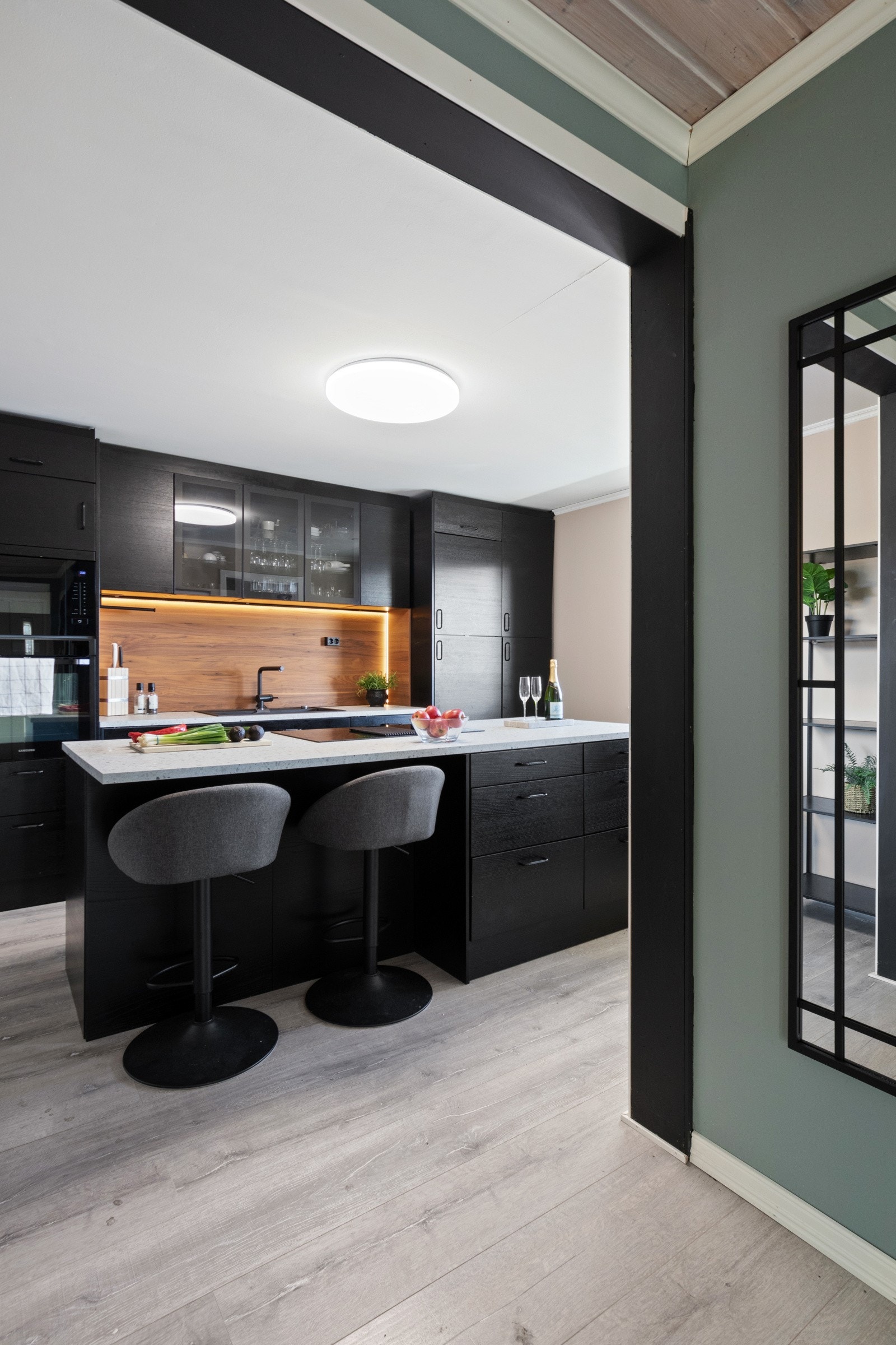 Entreen glir sømløst over i et flott kjøkken, der laminatgulvet bidrar til den flytende overgangen. Galleribilde