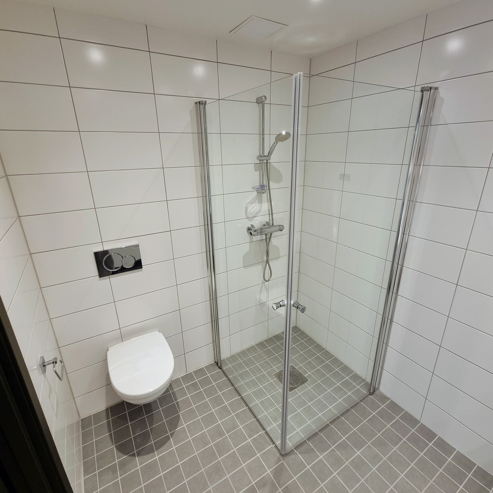 Hybelens våtrom har flislagt gulv med varmekabler, flislagte vegger og opplegg for vaskemaskin. Galleribilde