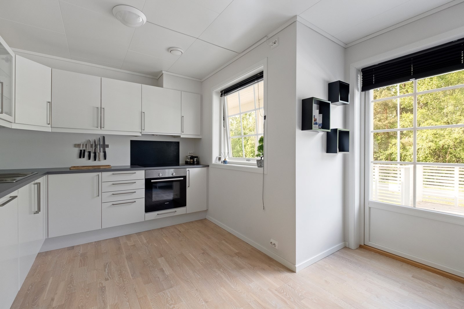 Kjøkkeninnredning i laminat med slette fronter. Det er ventilator over integrert komfyr, integrert oppvaskmaskin, kjøl- og fryseskap. Laminat benkeplate med nedfelt dobbel oppvaskkum. Galleribilde