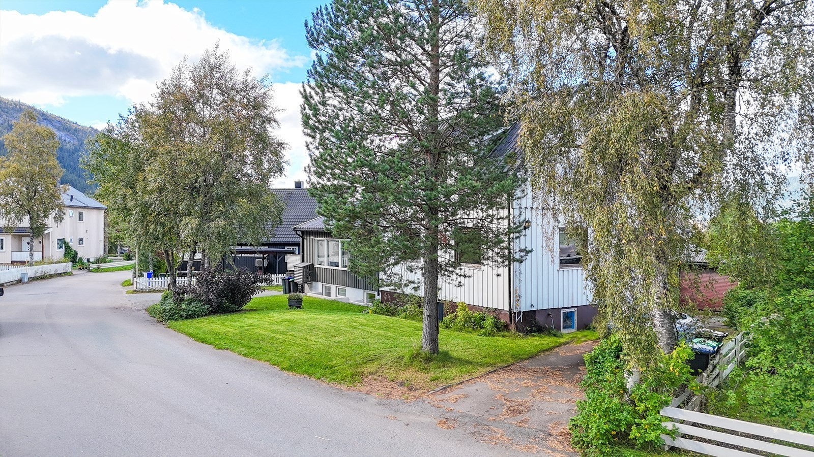 Eiendommen ligger skjermet til, omkranset av bjørketrær og prydbusker. Galleribilde