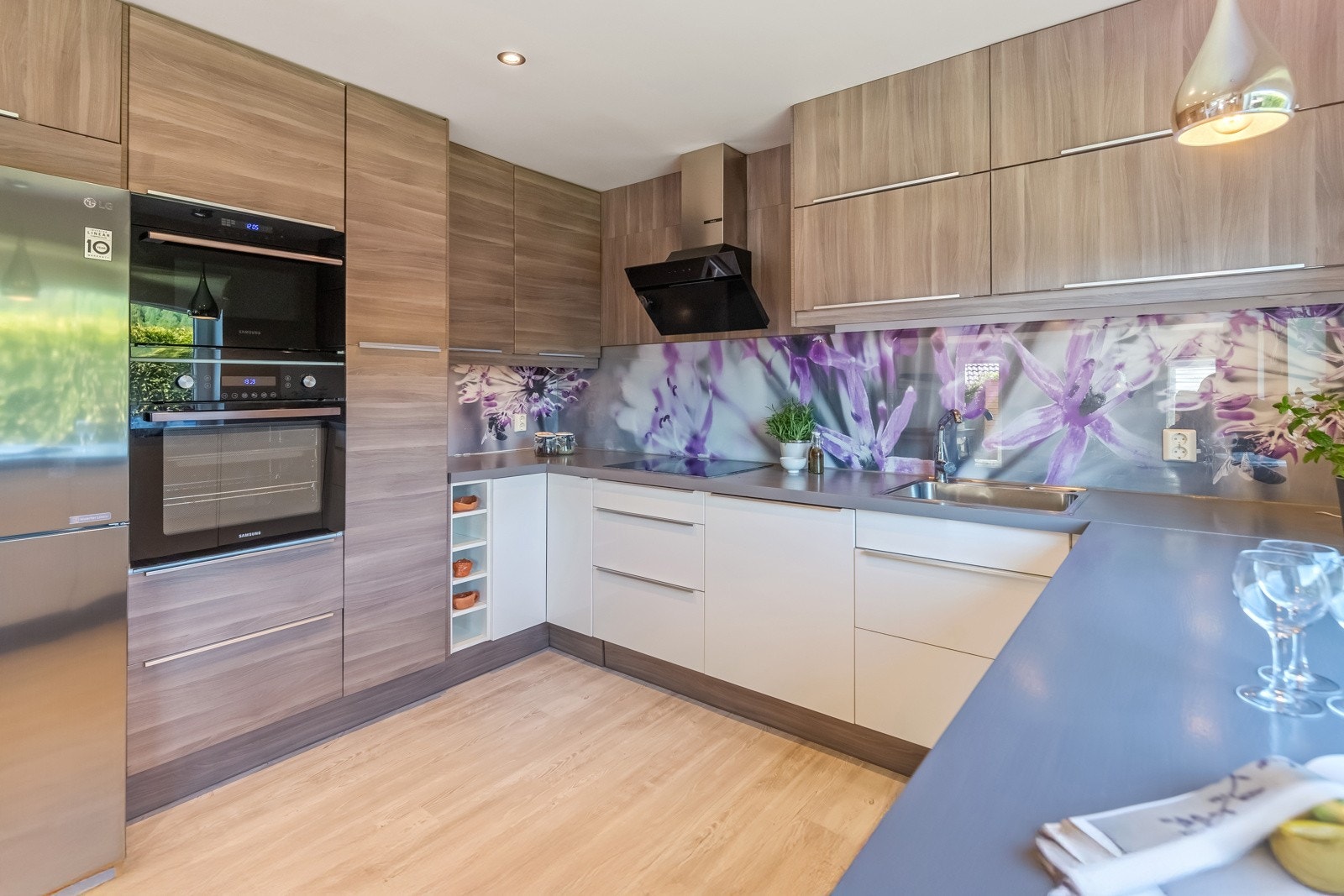 Heltre benkeplate med vannfast plate over benk ved vask/komfyr. Integrert induksjonstopp, stekeovn, mikrobølgeovn og oppvaskmaskin. Galleribilde