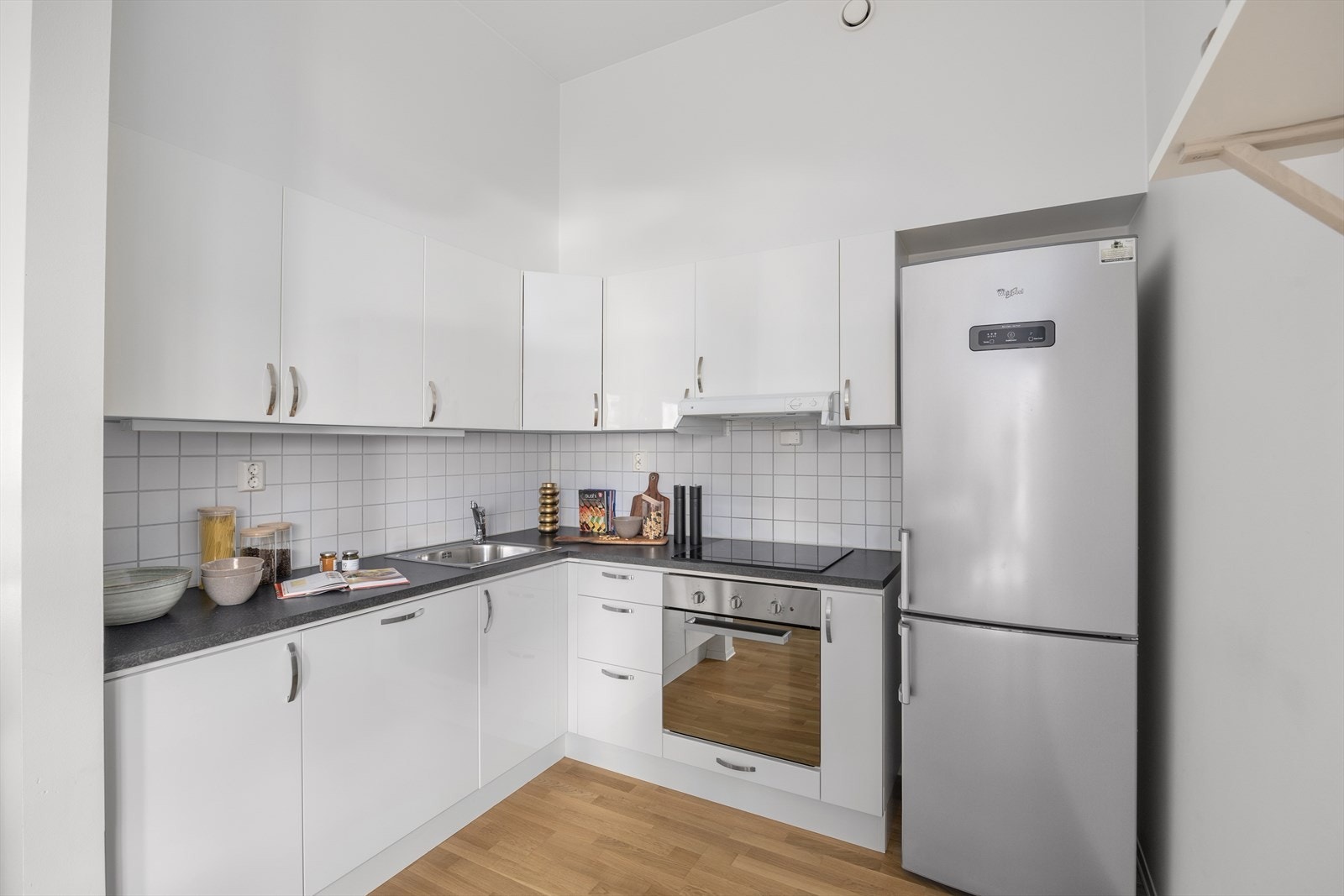 Flott kjøkken med integrerte hvitevarer og frittstående kjøle-/fryseskap Galleribilde