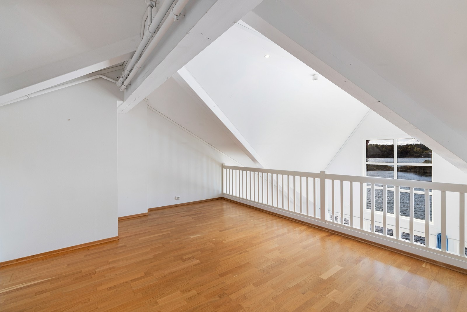 Innredet loftstue med utsikt og hvor det er åpent ned til stue. Galleribilde