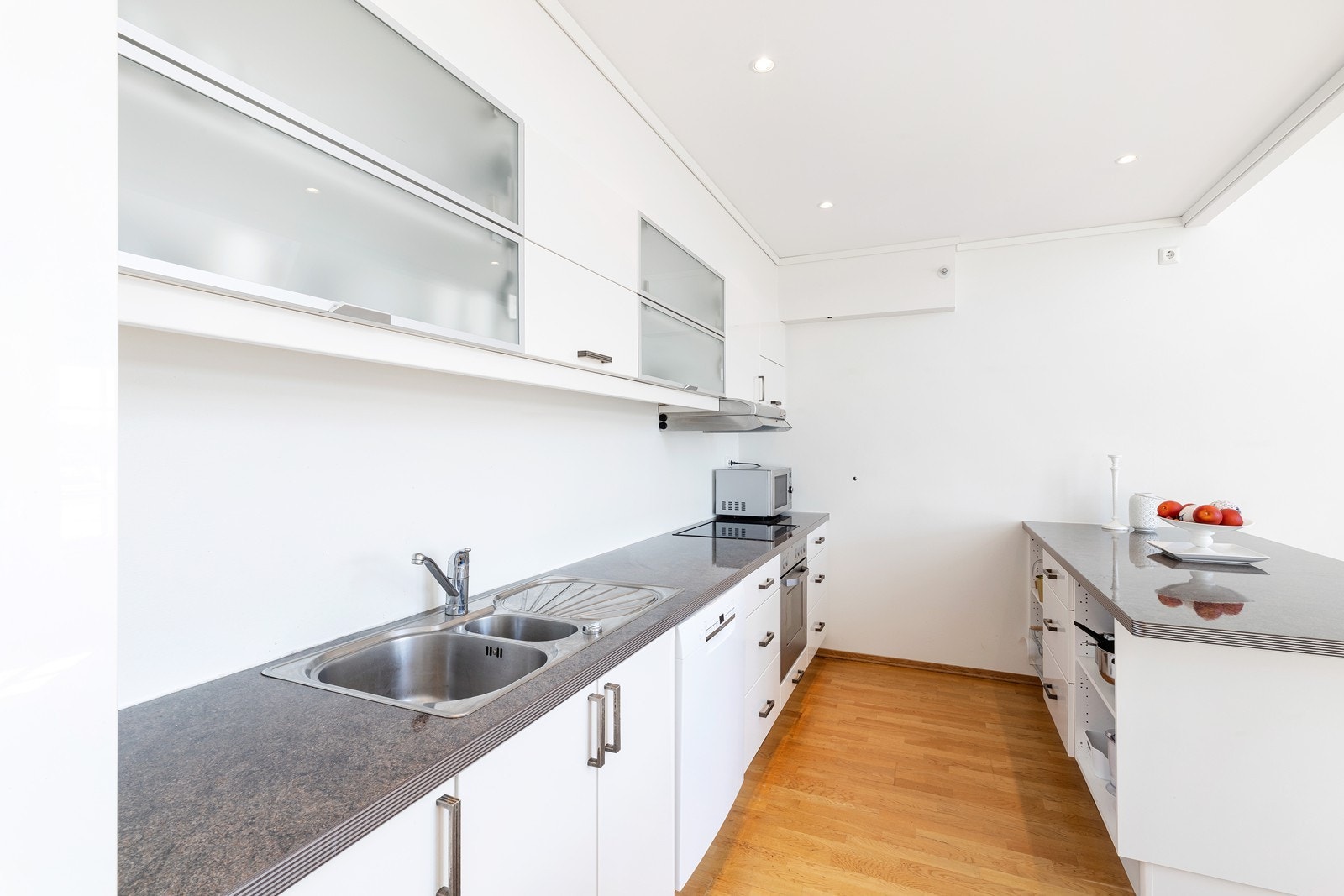 Kjøkken med hvite glatte fronter og laminat benkeplate. Hvitevarer medfølger salget. Galleribilde