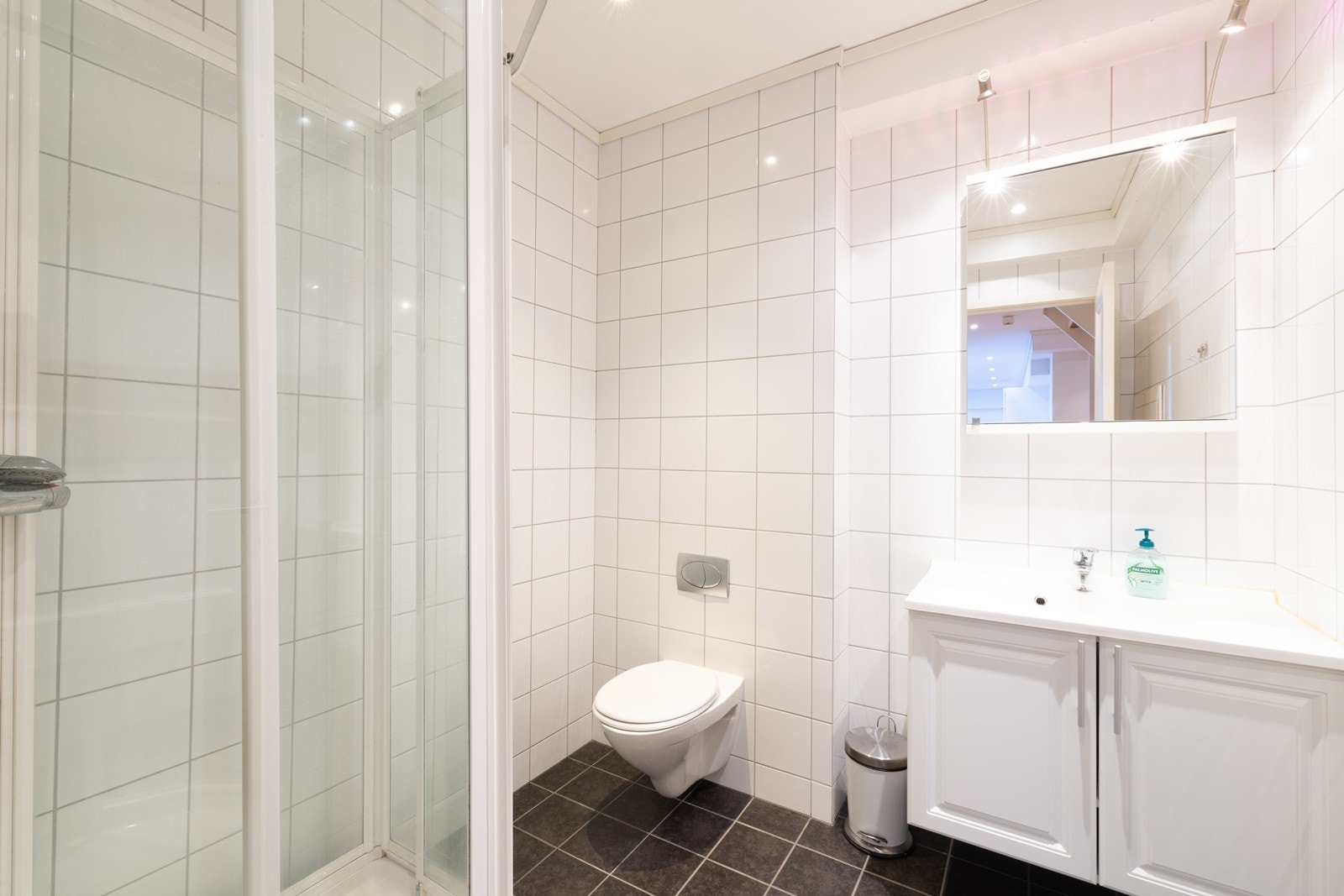 Flislagt bad med dusjkabinett, vegghengt toalett og servant med underskap. Galleribilde