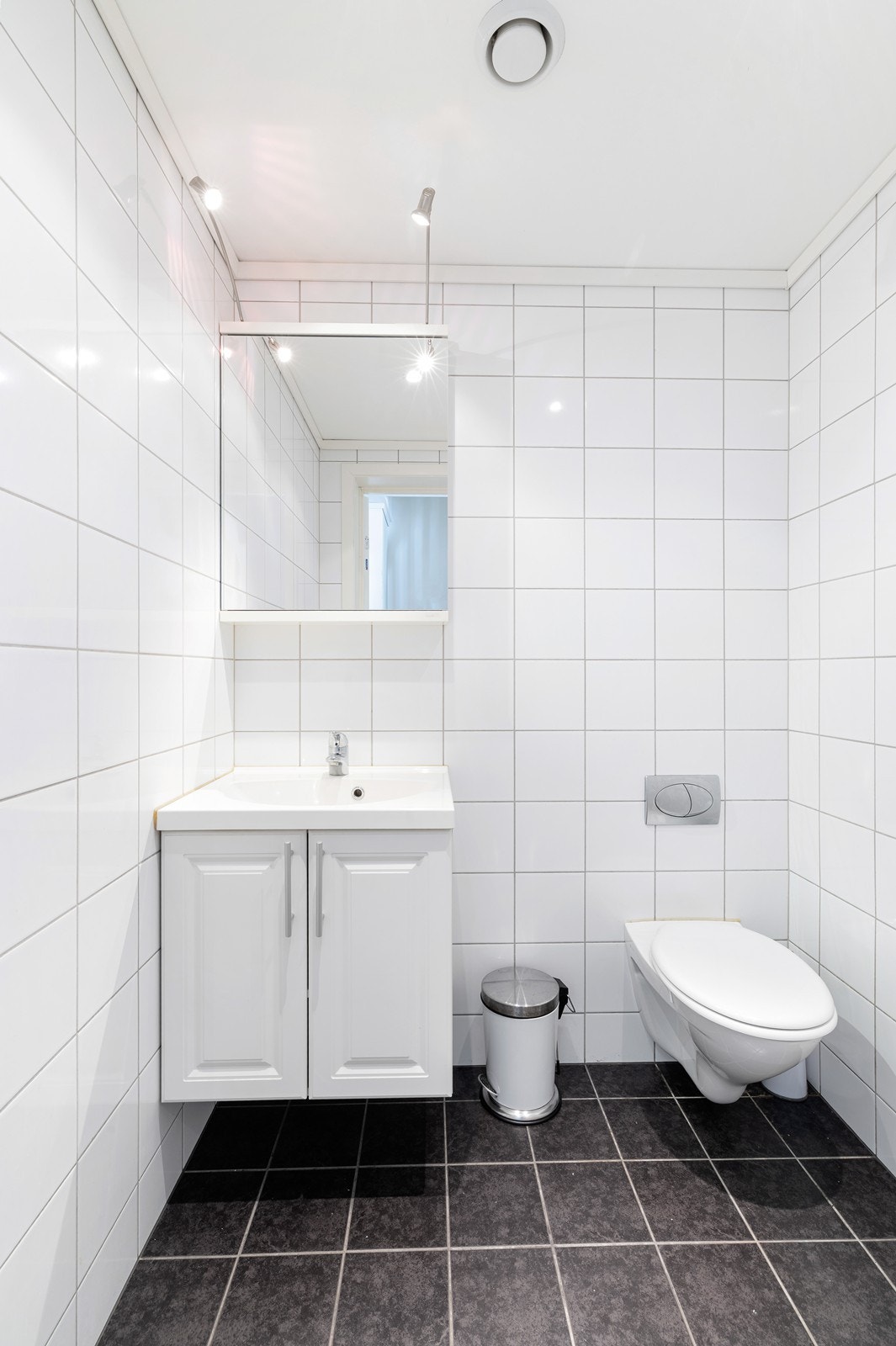 Flislagt gjestetoalett med vegghengt toalett, servant med underskap. Galleribilde