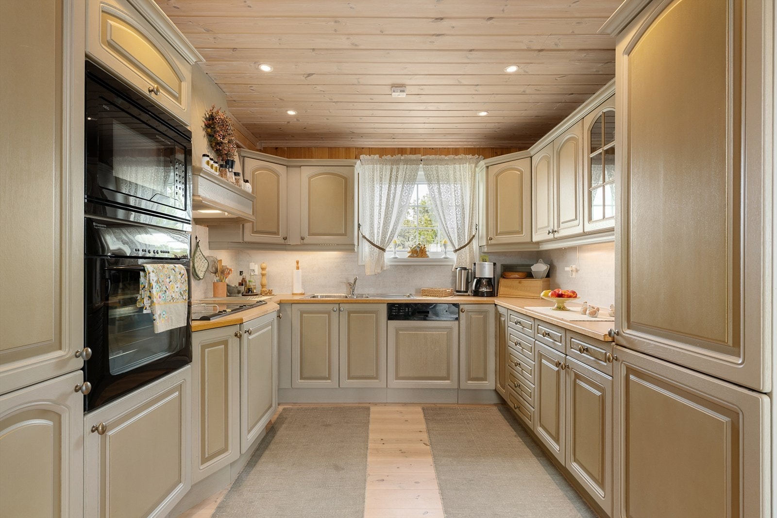 Lyst og flott kjøkken som har rikelig med skapplass. Fint lys inn i rommet gjennom vindu over kjøkkenbenken. Galleribilde