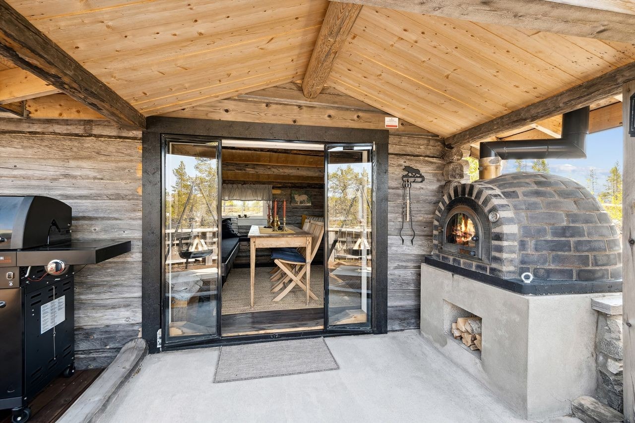 Meget koselig stue i tømmerstua med fine glassdører og overbygg ved utepeisen Galleribilde