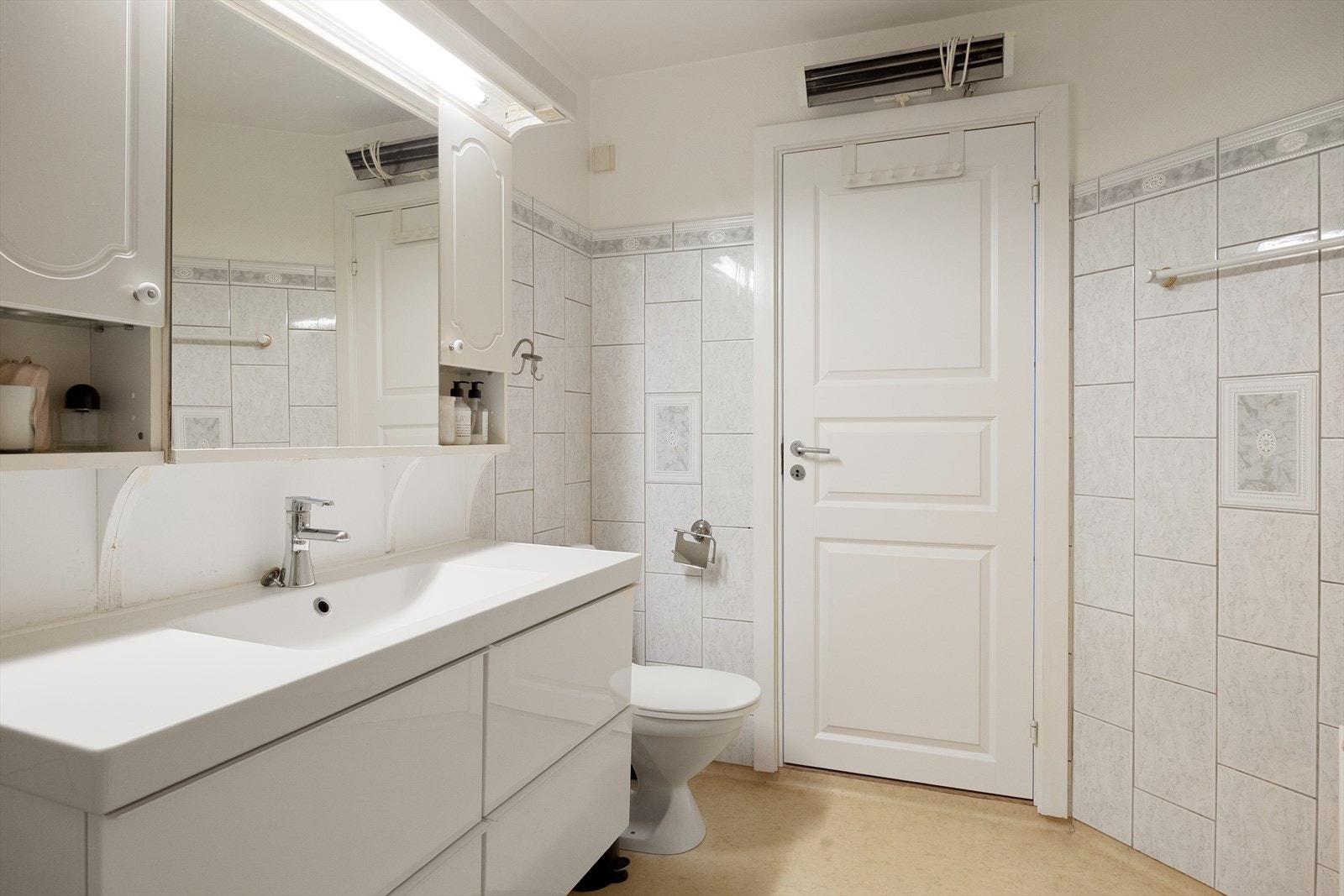 Romslig bad med servant med god plass til oppbevaring, toalett, speilskap m.m. Galleribilde