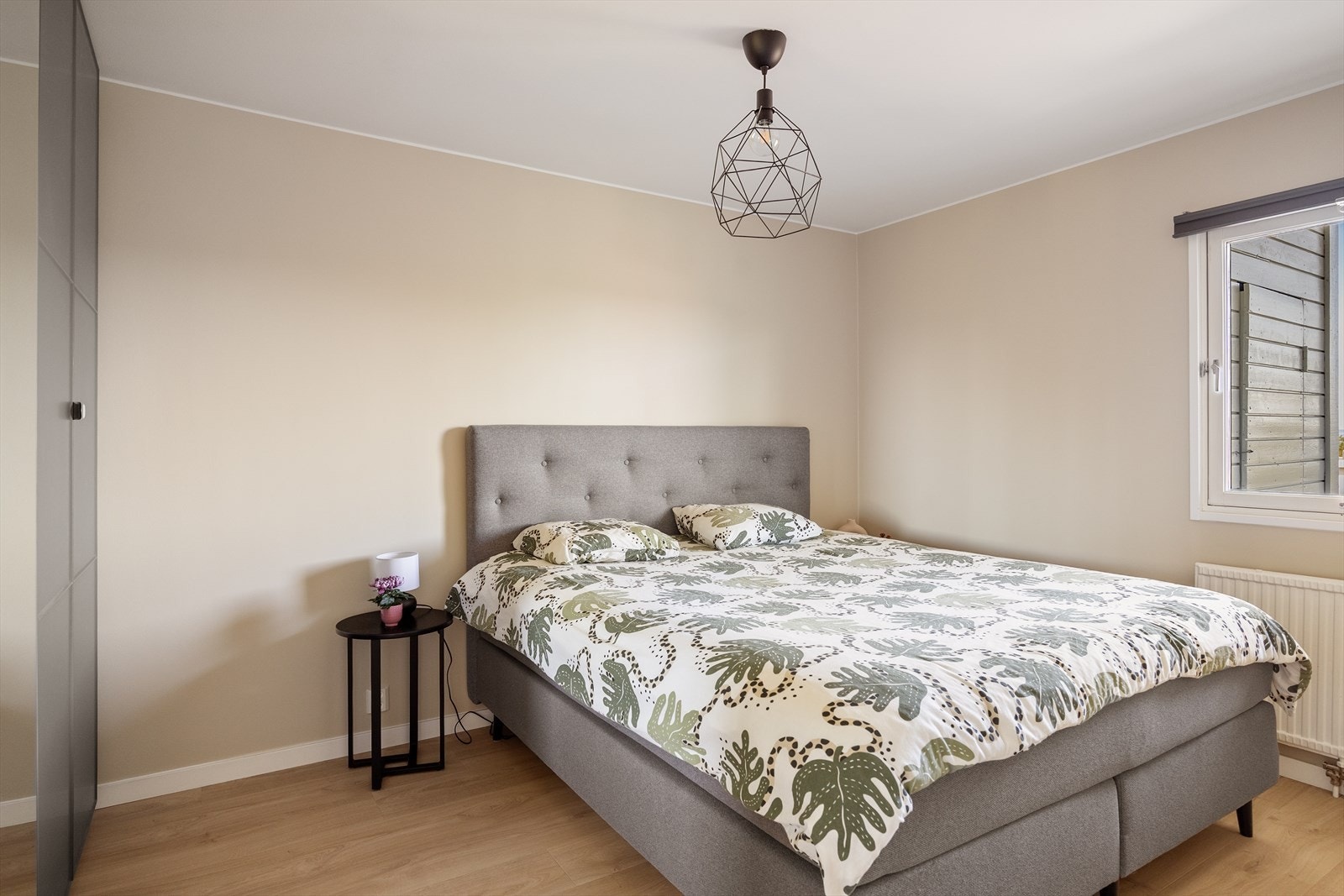 Romslig soverom med plass til stor dobbeltseng og tilhørende nattbord Galleribilde