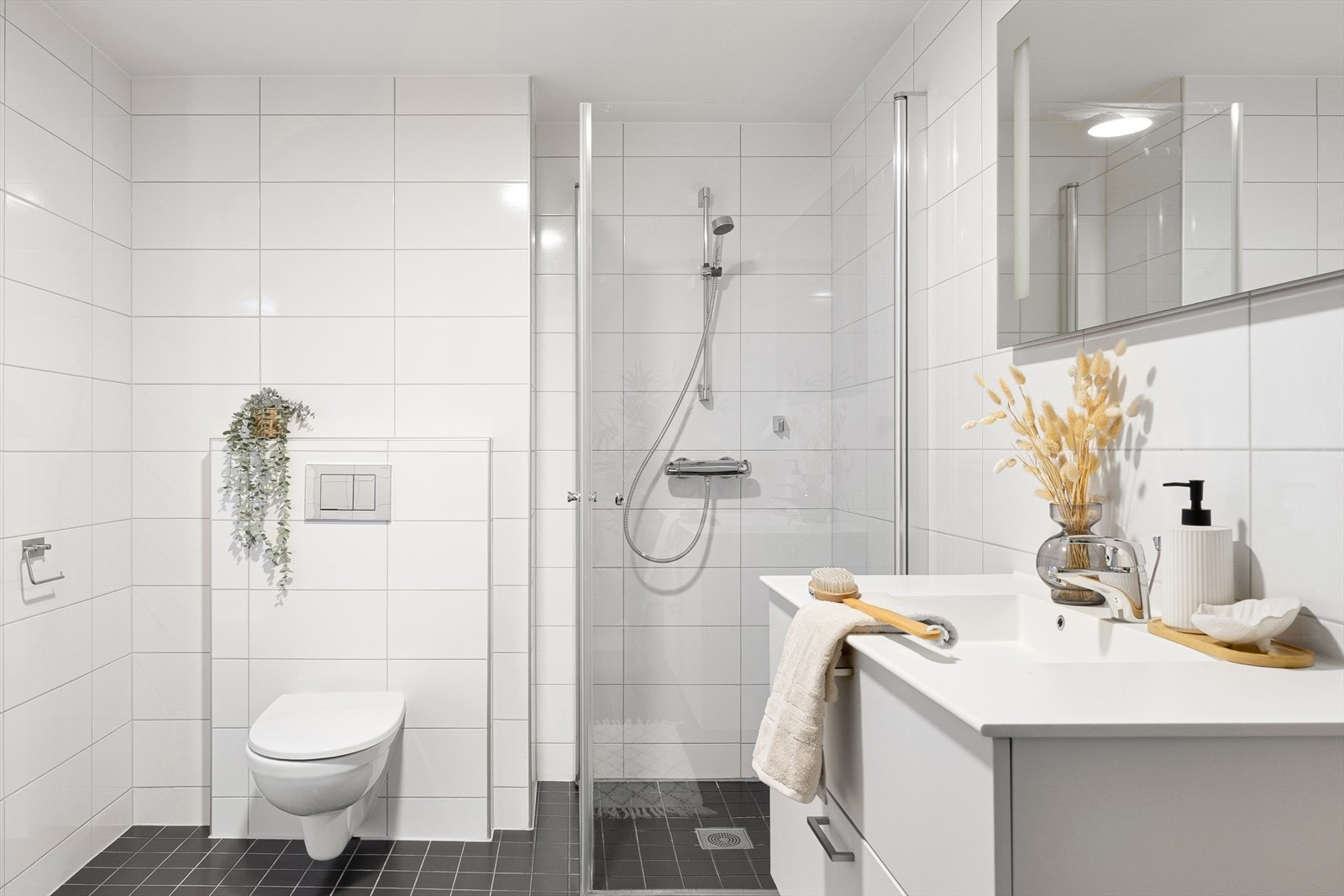 Badet er innredet med dusjhjørne, nedfelt servant i møbel og vegghengt toalett. Galleribilde