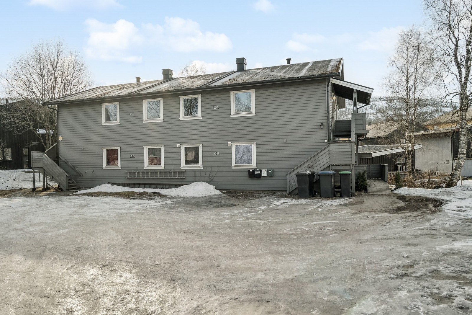 Parkering utenfor bygget, på felles parkeringsplass. Leiligheten ligger oppe til høyre i bygget. Galleribilde