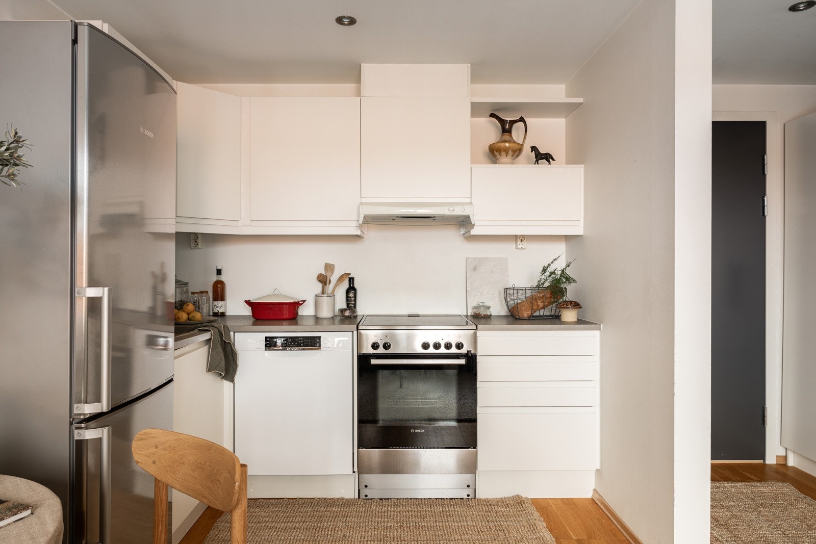 Den åpne kjøkkenløsningen glir sømløst inn i stuen og skaper en harmonisk og sosial sone der både matlaging og samvær står i sentrum. Ventilator montert i overskap med avtrekk til balansert ventilasjon. Galleribilde