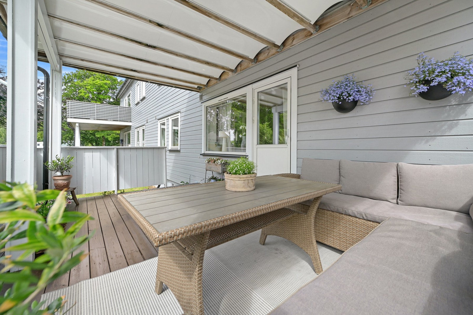 Fra stuen er det utgang til overbygget veranda på 17 m² hvor man kan nyte lange sommerkvelder. Terrassebordene ble beiset i 2025. Galleribilde