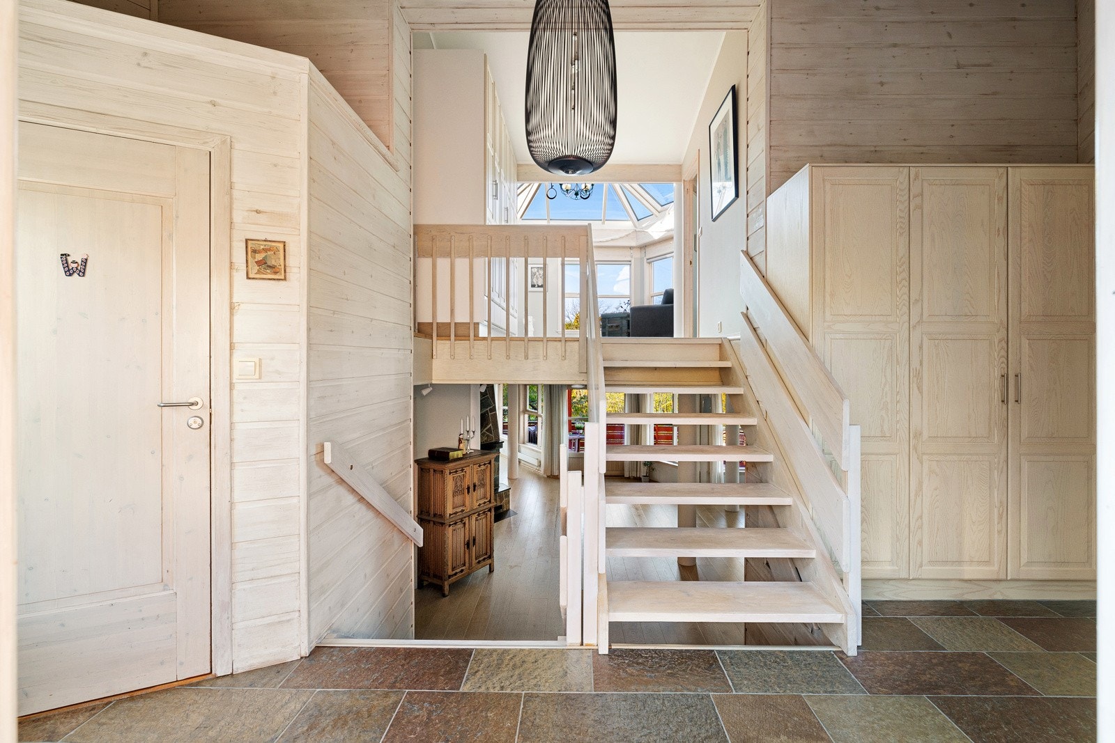 Velkommen inn - En romslig skiferbelagt entré med rikelig skapplass i pent plassbygd garderobeskap. Galleribilde