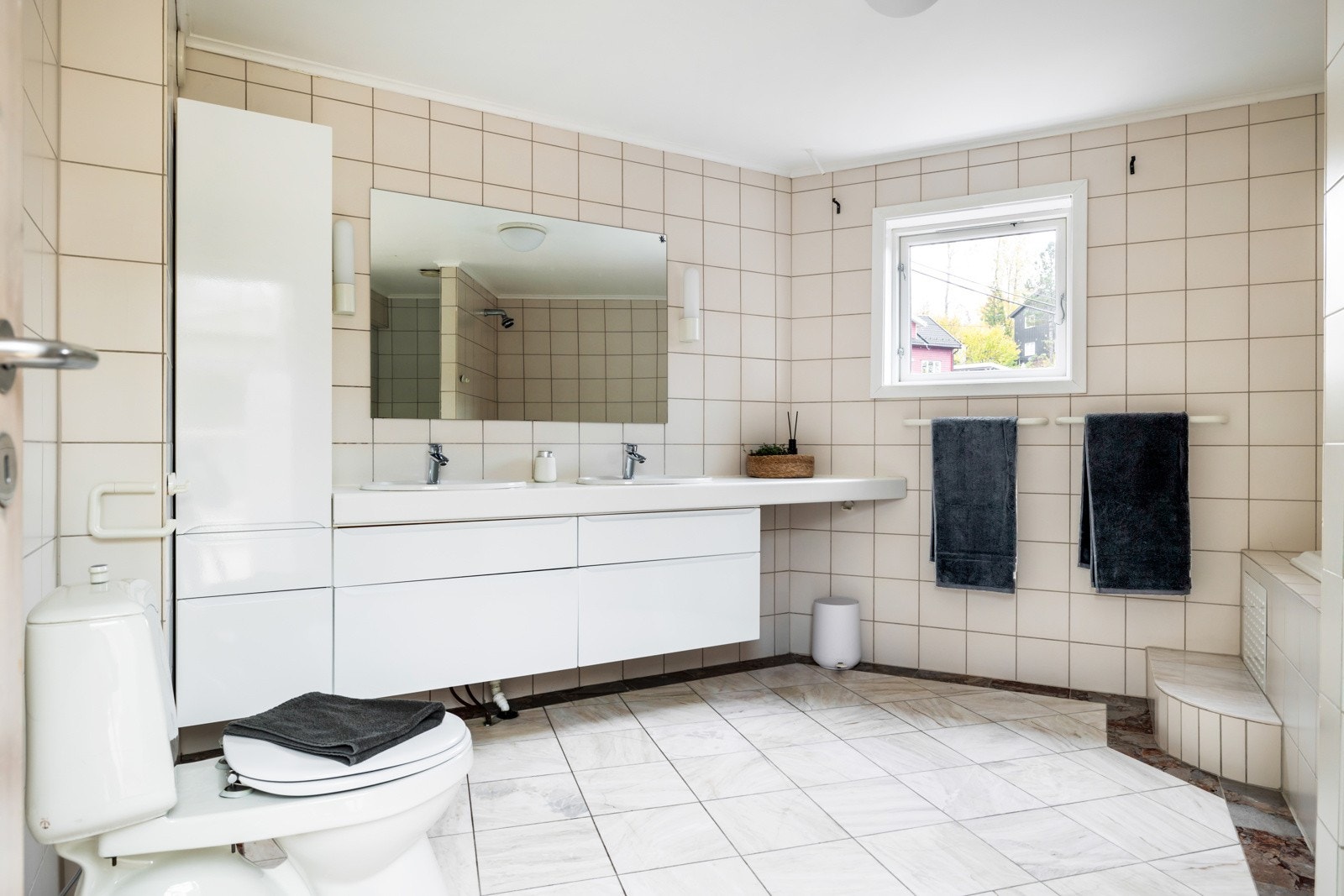 Stort flislagt hovedbad med flotte marmorfliser på gulvet og behagelig gulvvarme. Galleribilde