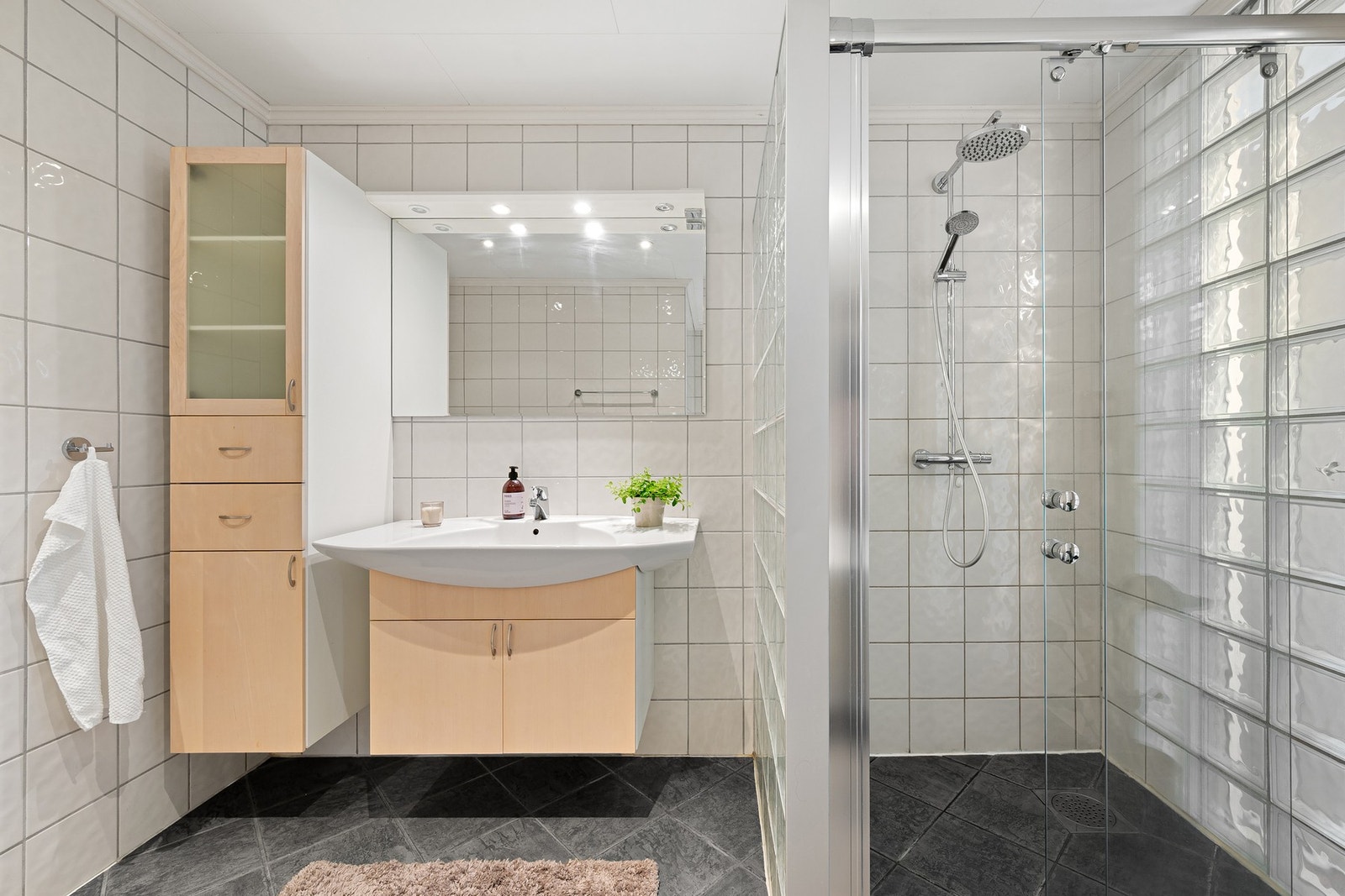 Stort bad med dusjhjørne, vegghengt innredning og flislagte overflater. Galleribilde