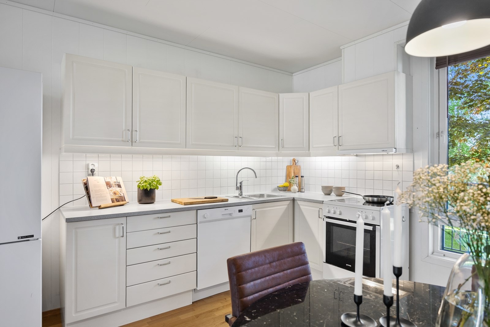 Kjøkkeninnredningen har hvite, profilerte fronter og laminert benkeplate. Galleribilde