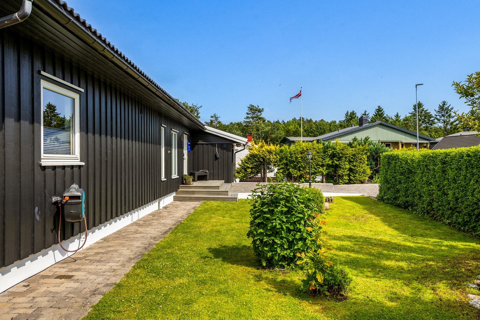I front av boligen ønsker en flott gangvei med belegningsstein deg velkommen, omkranset av en velstelt og innbydende gressplen. Galleribilde