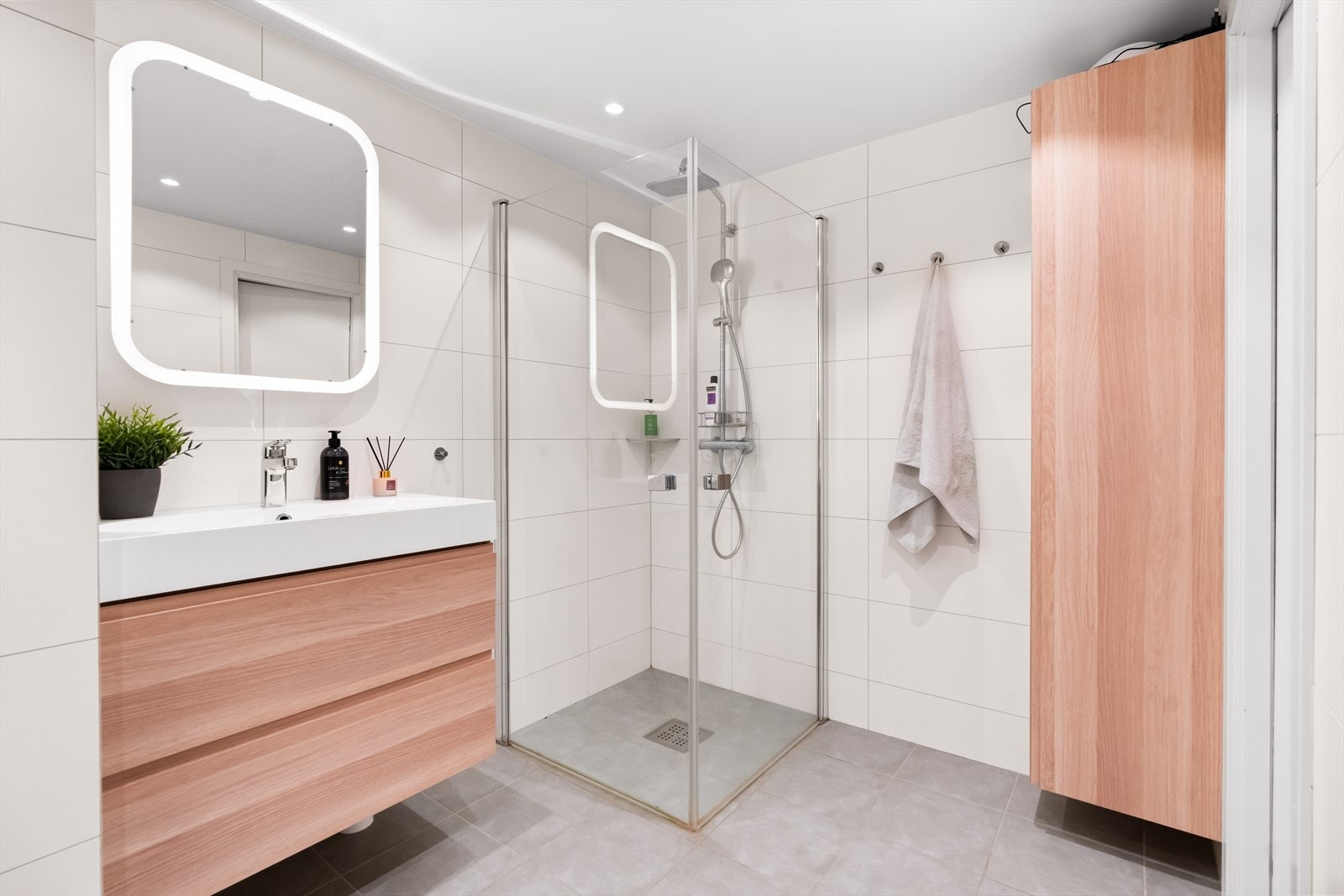 Videre er badet utstyrt med opplegg for vaskemaskin, veggmontert toalett samt dusjhjørne med svingdører, regnfallsdusj, håndholdt dusj og termostatstyrt blandebatteri. Badet har mekanisk avtrekk. Galleribilde