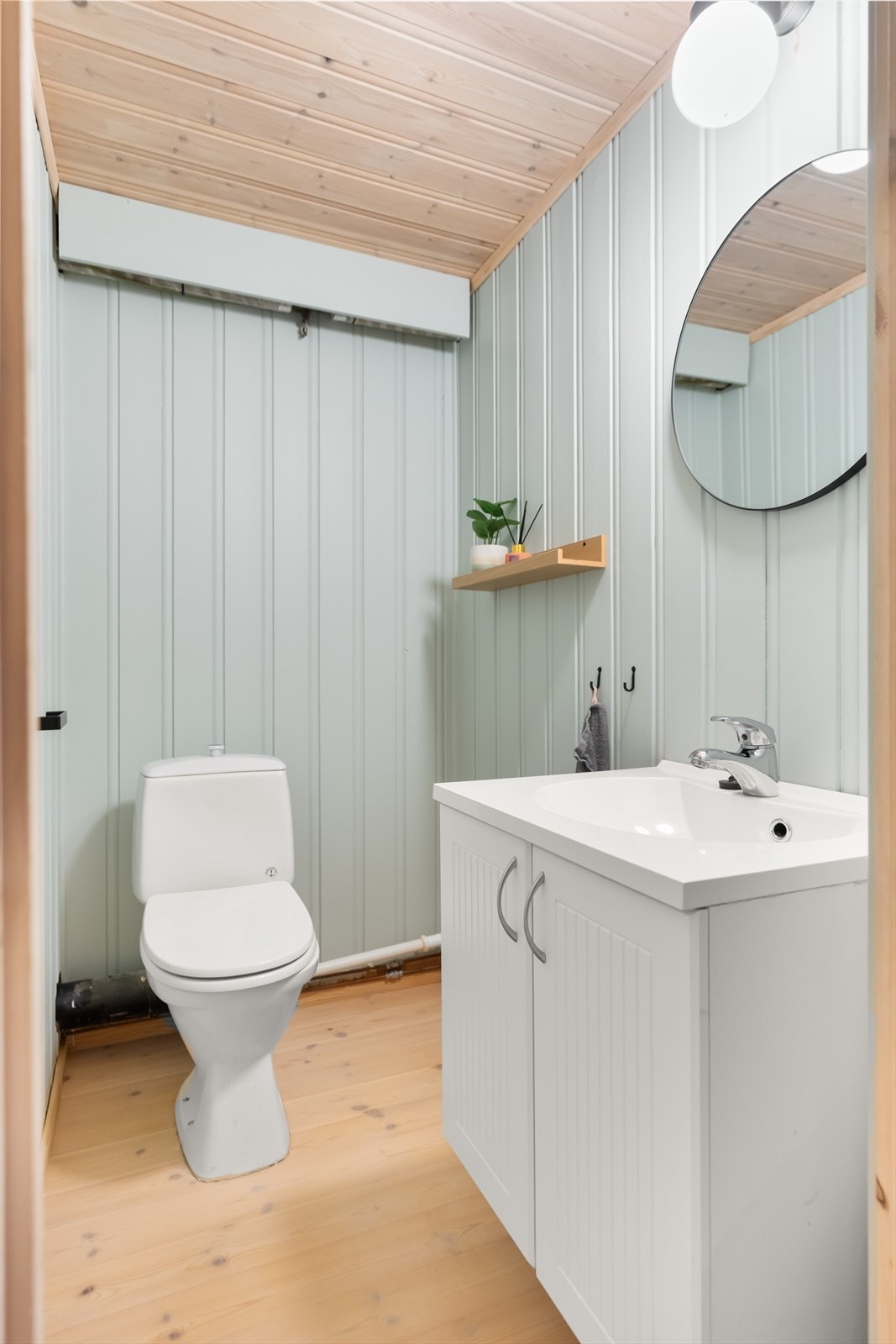Separat toalettrom med gulvbord av heltre, ellers glatte, malte, flater i himling og vegger. Rommet har vegghengt servant med speil over. I tillegg er det satt inn gulvstående toalett. Galleribilde