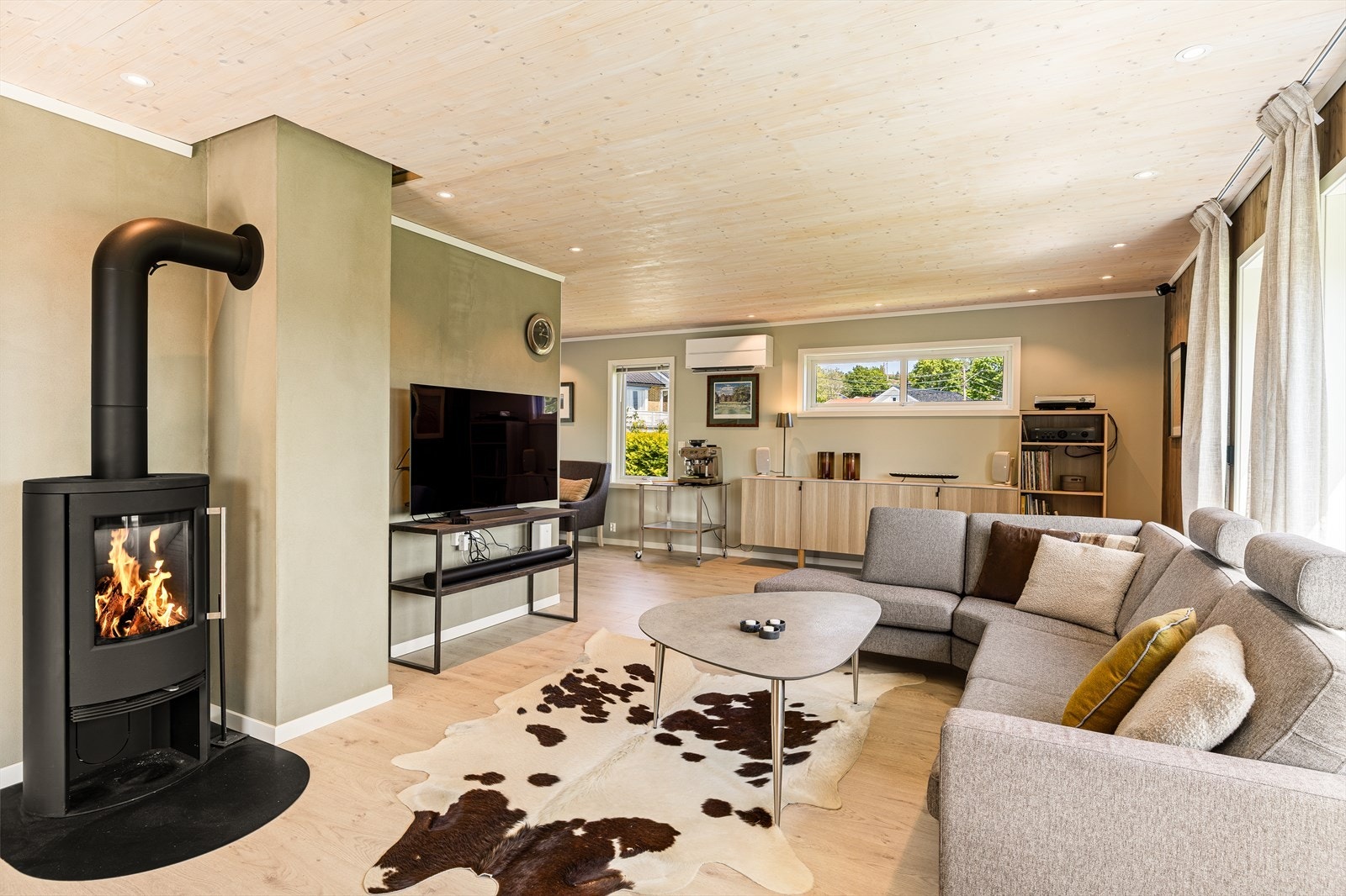 Stuen er malt i en nydelig, moderne fargetone som skaper en lun og behagelig atmosfære. Rommet har en stilfull og tidløs innredning med gjennomgående pene overflater og nydelige gulv som harmonerer godt med resten av boligens uttrykk. Galleribilde