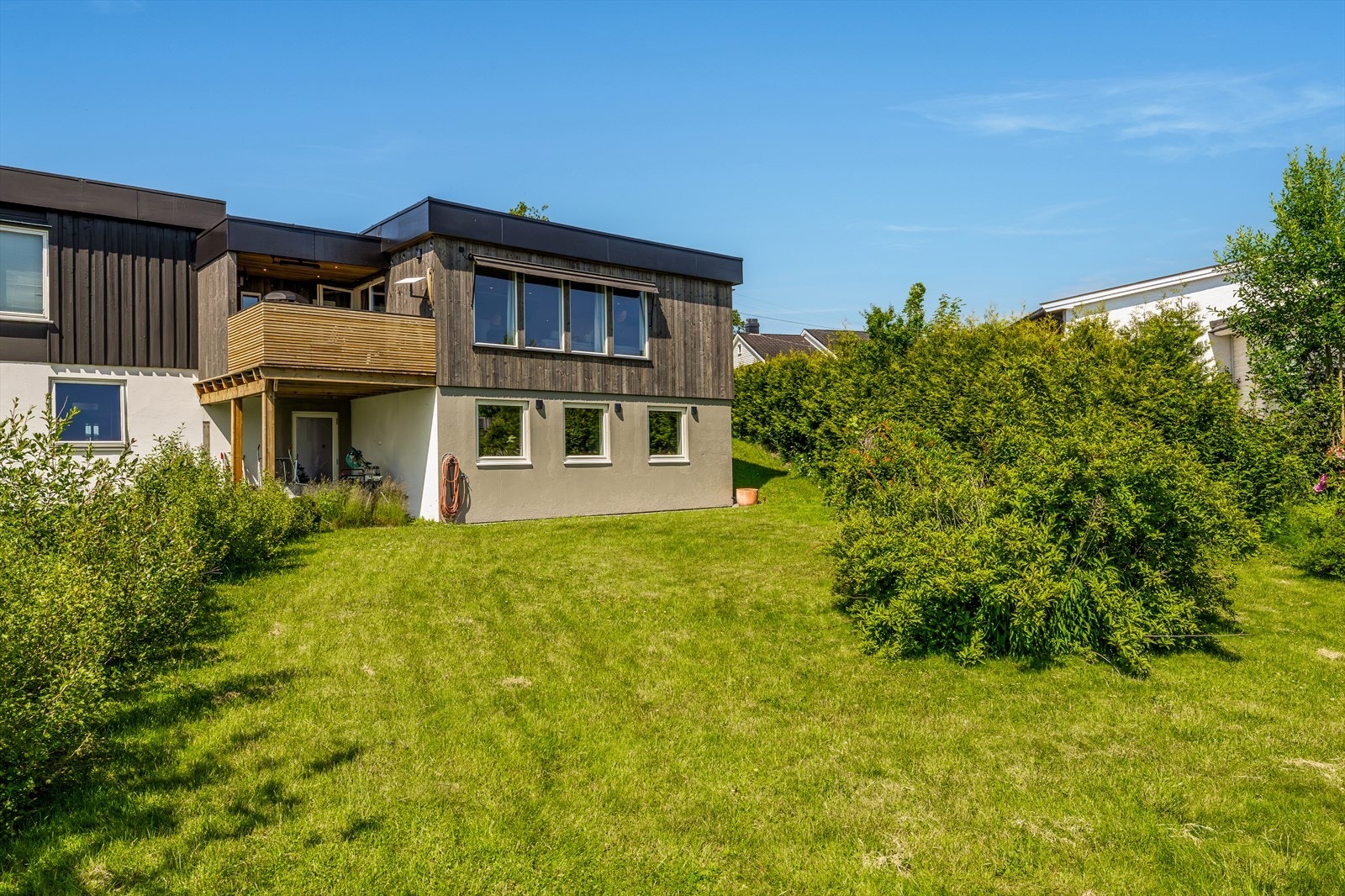 Hagen er pent opparbeidet med gressplen og velvoksne hekkplanter som gir en grønn, lun ramme rundt eiendommen. Her er det god plass til lek, hageaktiviteter eller en rolig stund i solen med en bok - alt i skjermede og behagelige omgivelser. Galleribilde