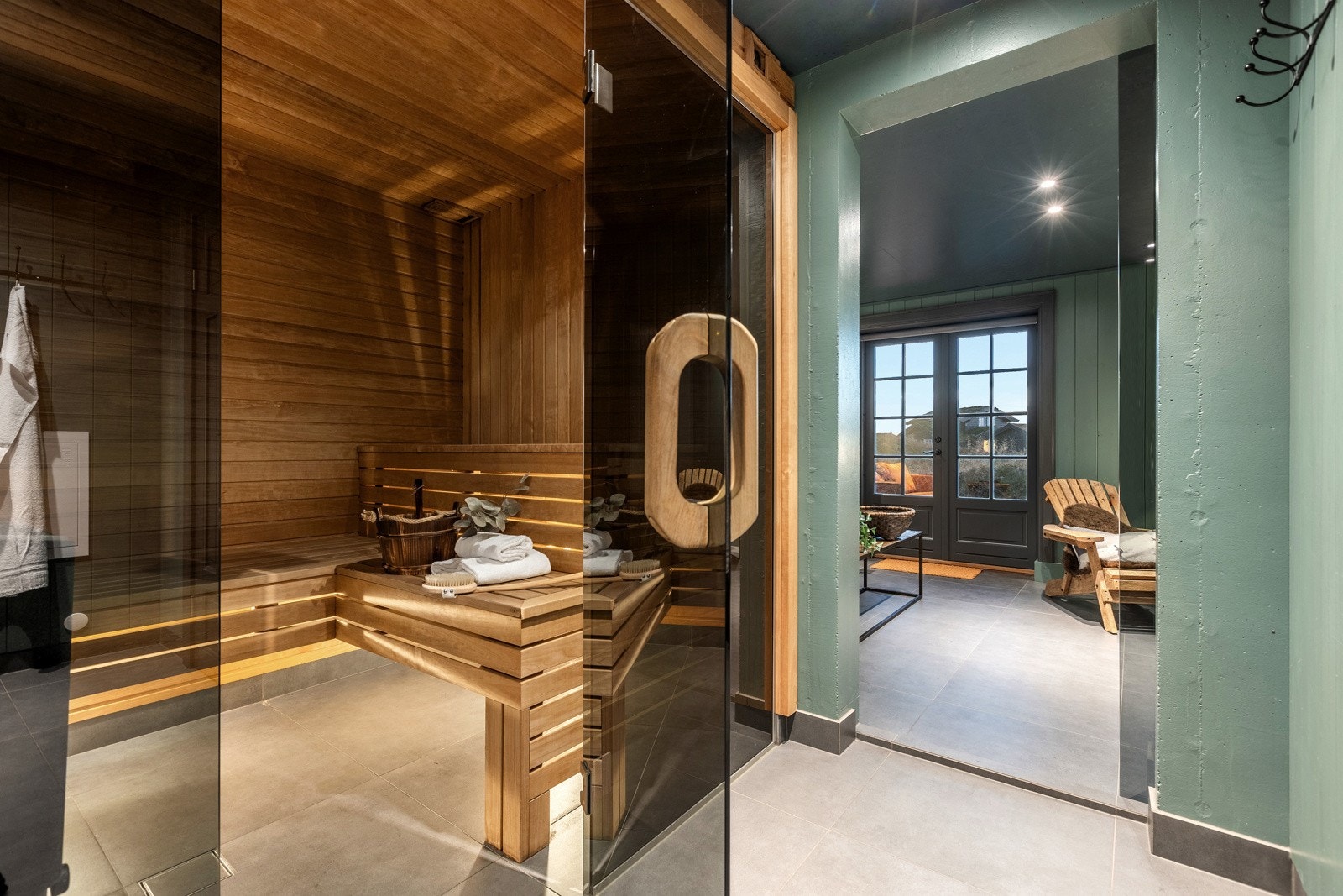 Dør inn til en badstue med benker i to høyder og elektrisk badstueovn. Galleribilde