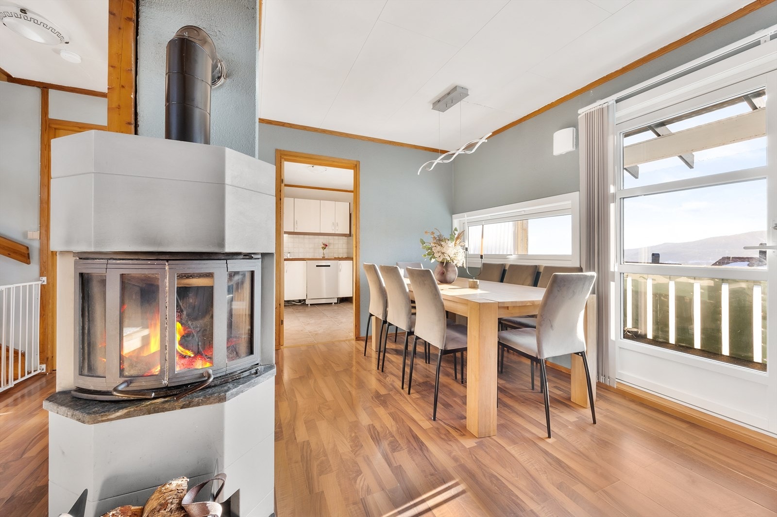 En lys og koselig spisestue med peis og store vinduer som slipper inn mye naturlig lys Galleribilde