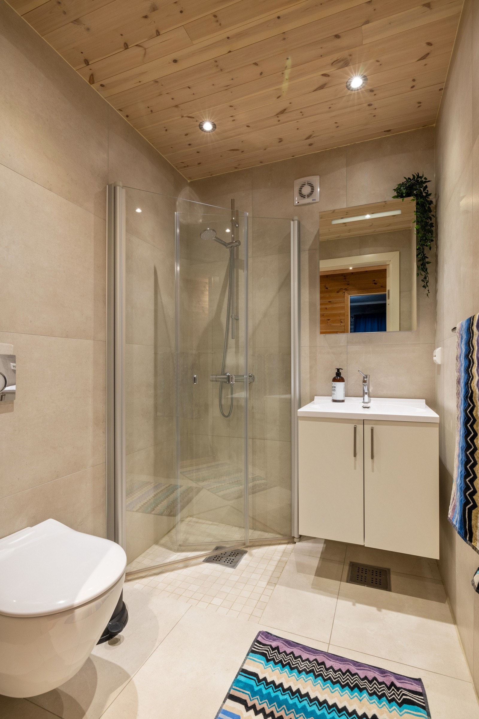 Begge bad med store lyse fliser på vegg og gulv, mosaikk i dusjnisje på bad 2 Galleribilde