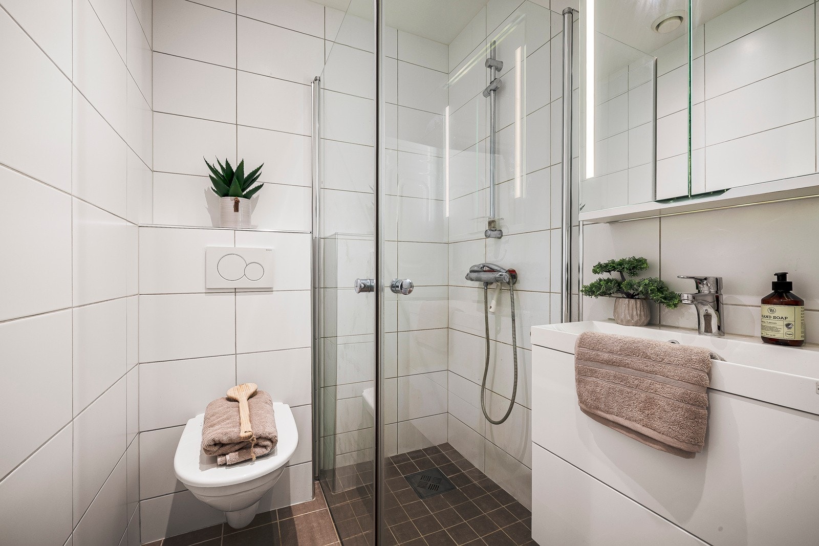 - Badet holder god størrelse og er innredet med fliser på gulv og vegger, vegghengt toalett, dusjhjørne med foldedører og servant med møblement - Galleribilde