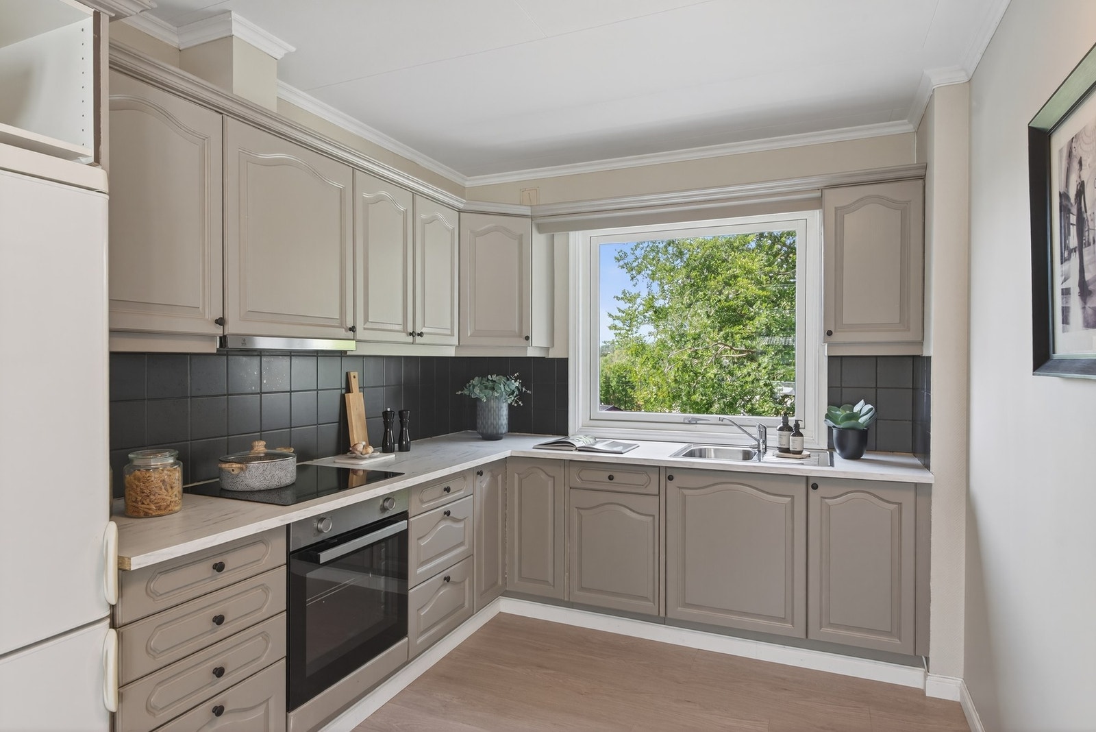 Kjøkkenet har lyse, profilerte fronter og mørke fliser som elegant viderefører kontrastene fra stuen og gir en helhetlig og moderne stil Galleribilde