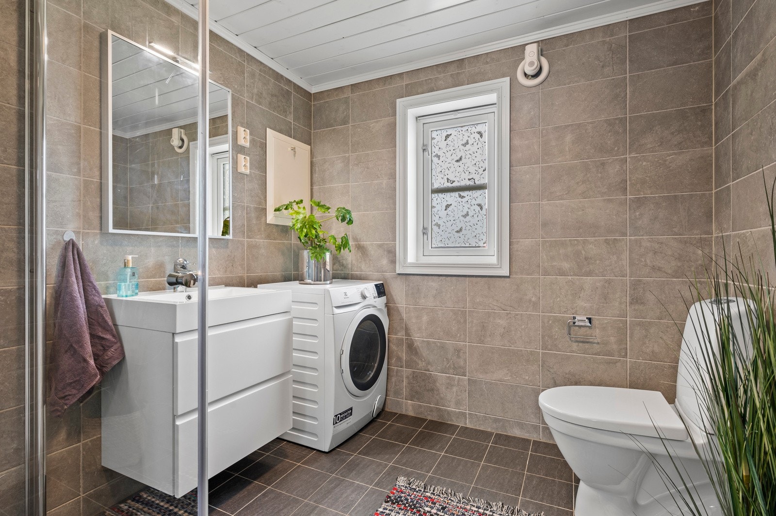 Flislagt bad med varmekabler i gulv og opplegg for vaskemaskin Galleribilde