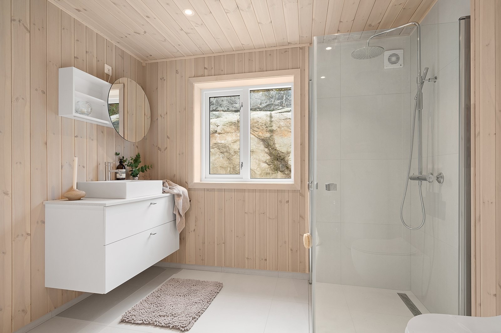 Badet har varmekabler i gulv og inneholder dusjhjørne, wc, opplegg til vaskemaskin og servant med underskap og speilskap. Galleribilde