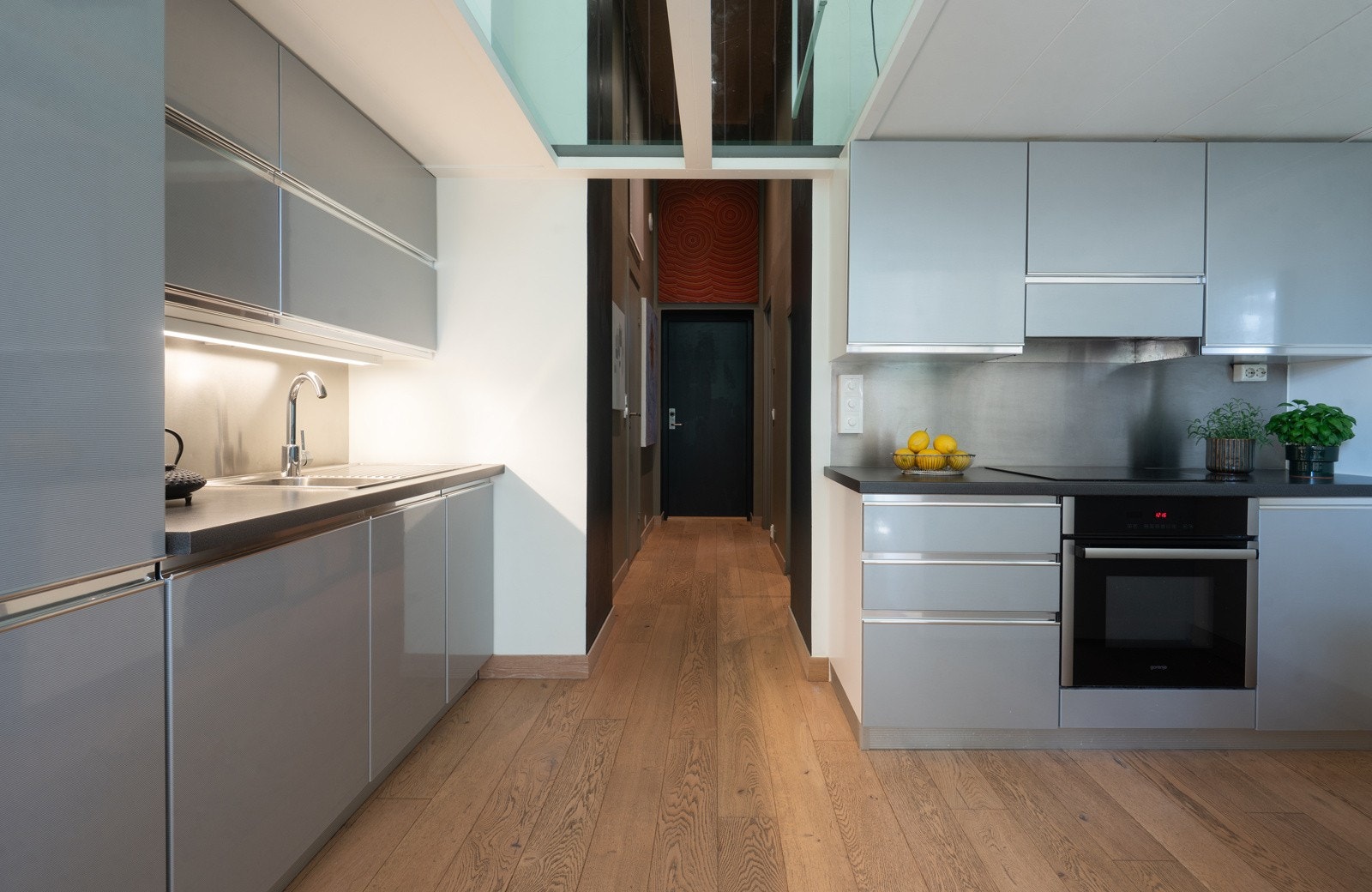 Den takhøye innredningen har glatte, nyere fronter i høyglans, mørk laminatbenkeplate, og nedfelt beslag med vaske- og skyllekum Galleribilde