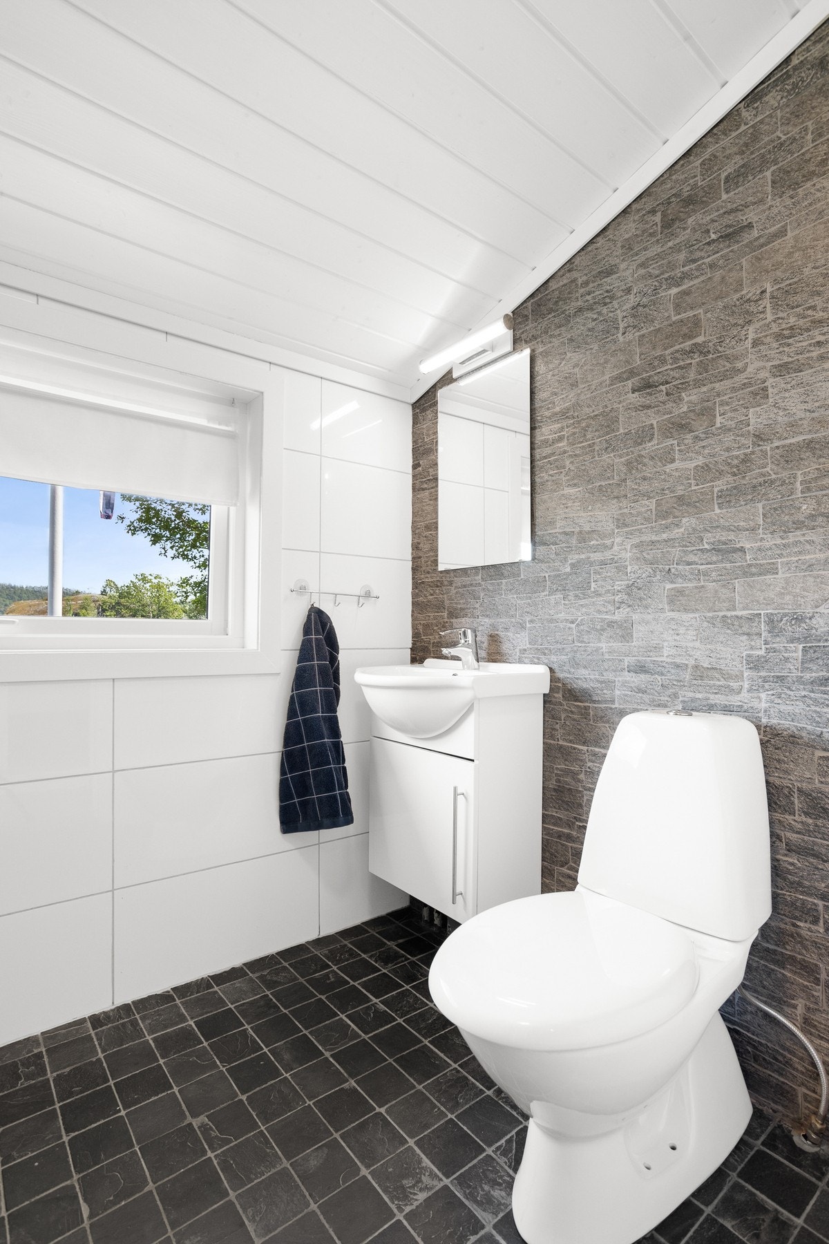 Pent bad som inneholder toalett, servant med innredning og dusjkabinett. Galleribilde