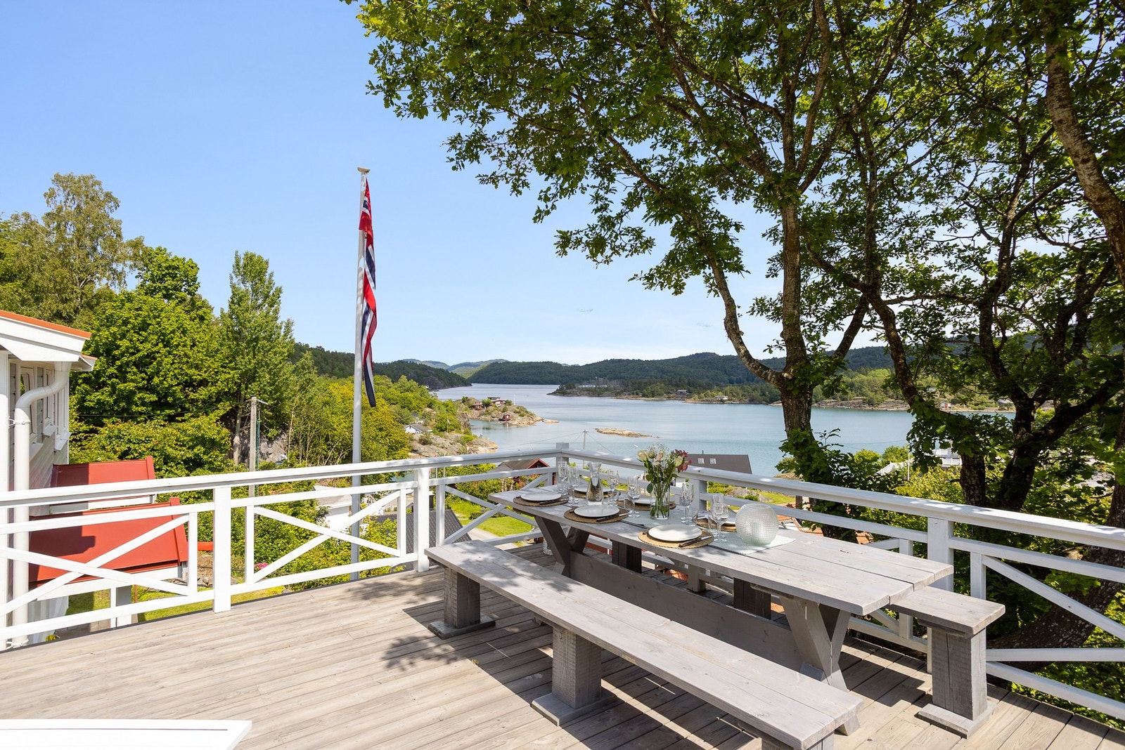 Fin utsikt mot sjøen fra hytte og uteområder. Galleribilde