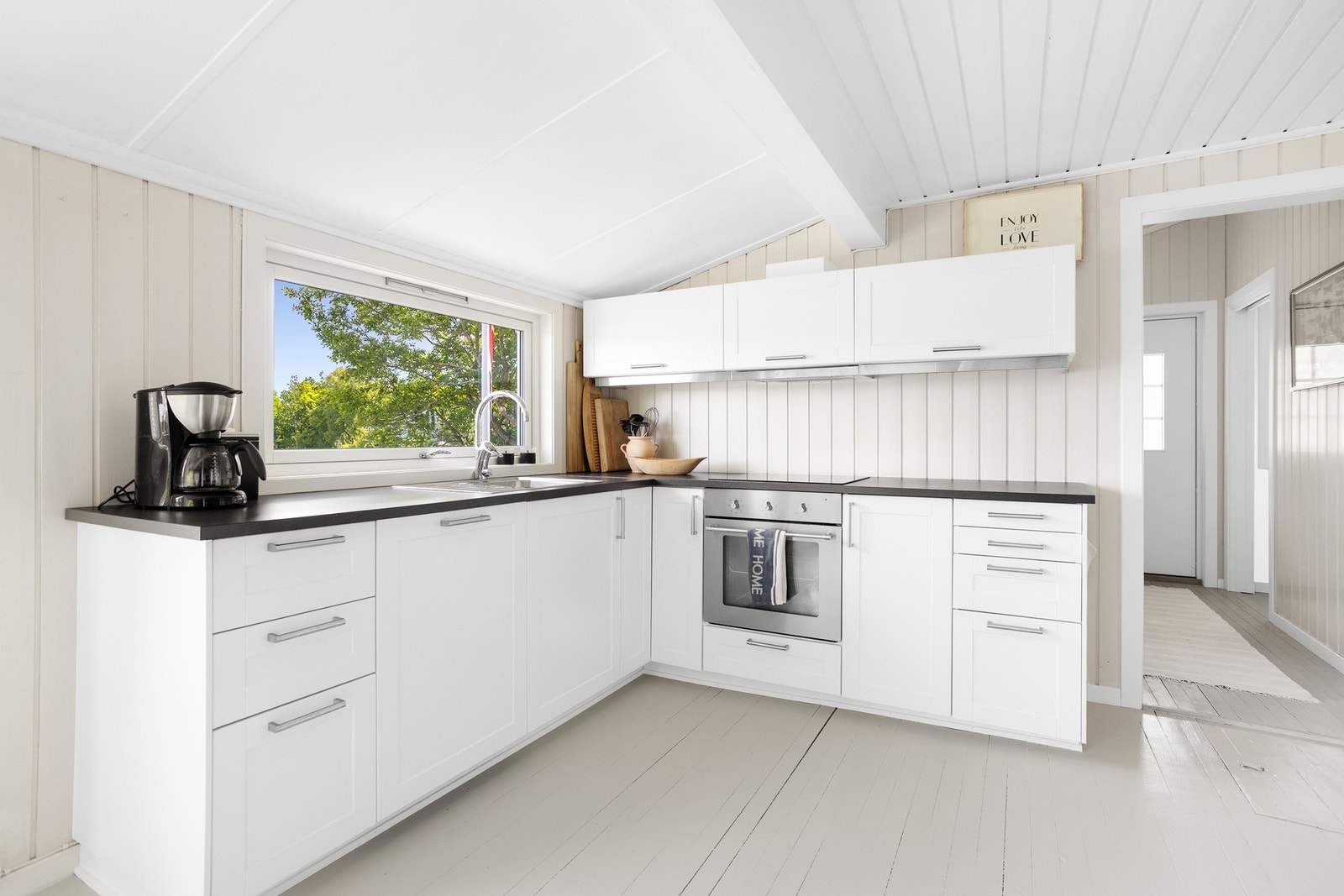 Pent IKEA kjøkken med integrerte hvitevarer som oppvaskmaskin, komfyr og platetopp. Galleribilde