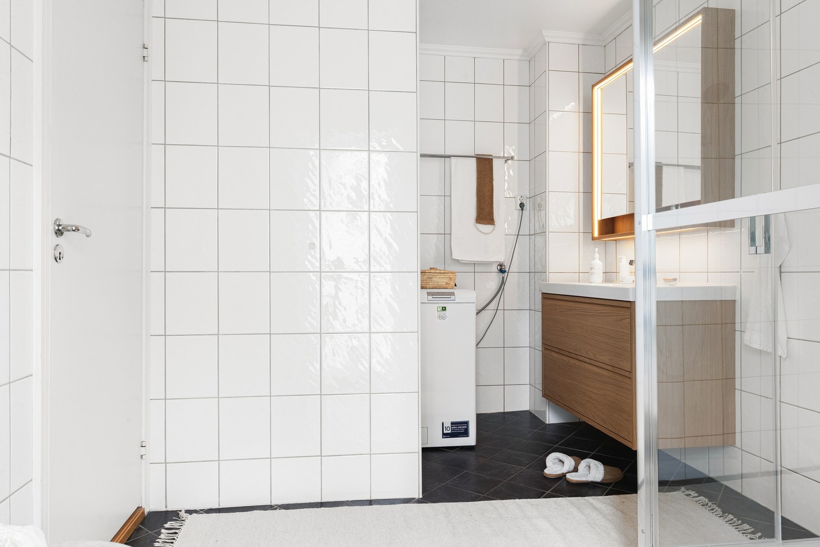 Her finner du moderne baderomsmøbler i eikeutførelse, speilskap med belysning, dusjkabinett og opplegg for vaskemaskin. Galleribilde