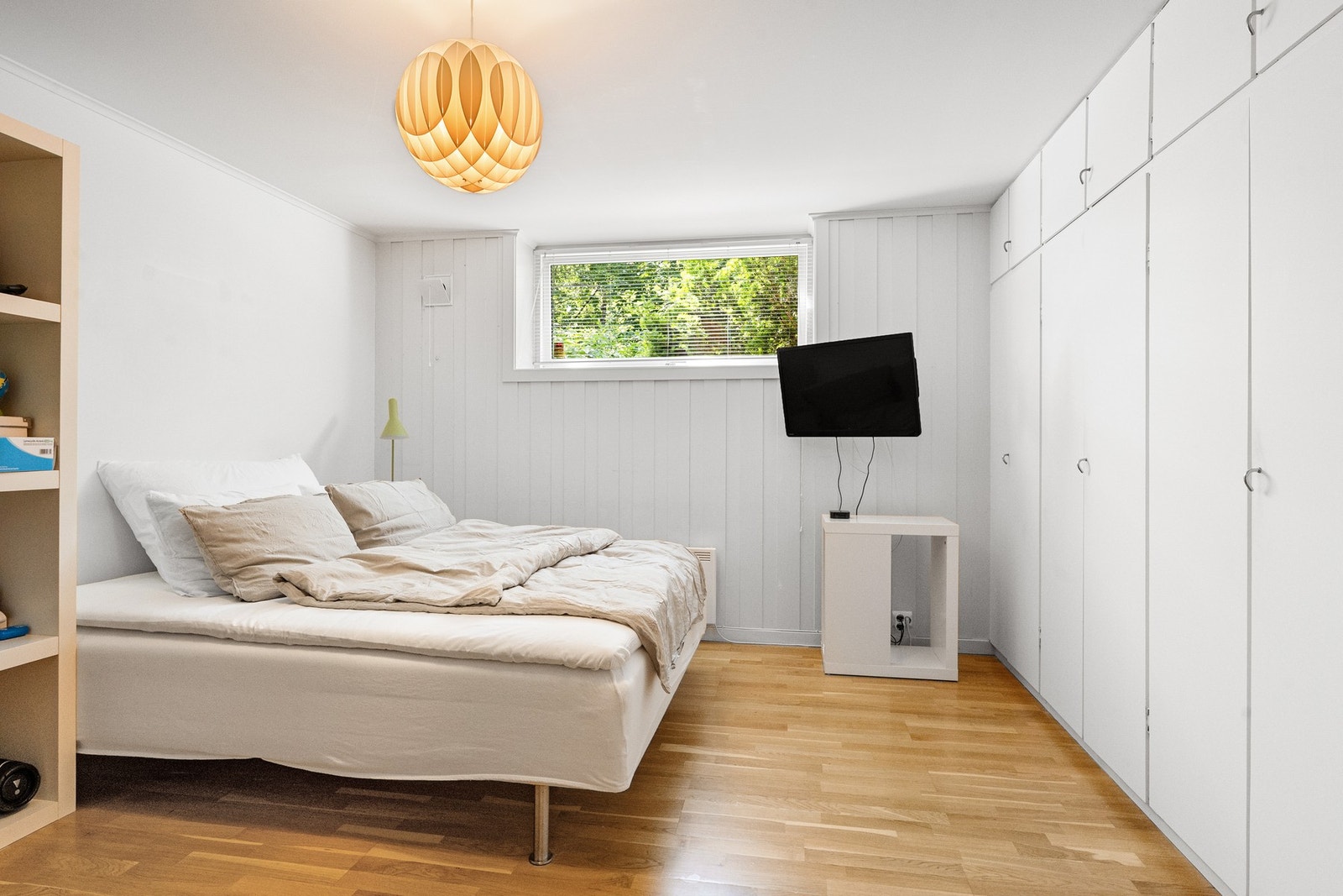 Lyst soverom med stor seng, vindu og garderobeskap langs veggen. Galleribilde