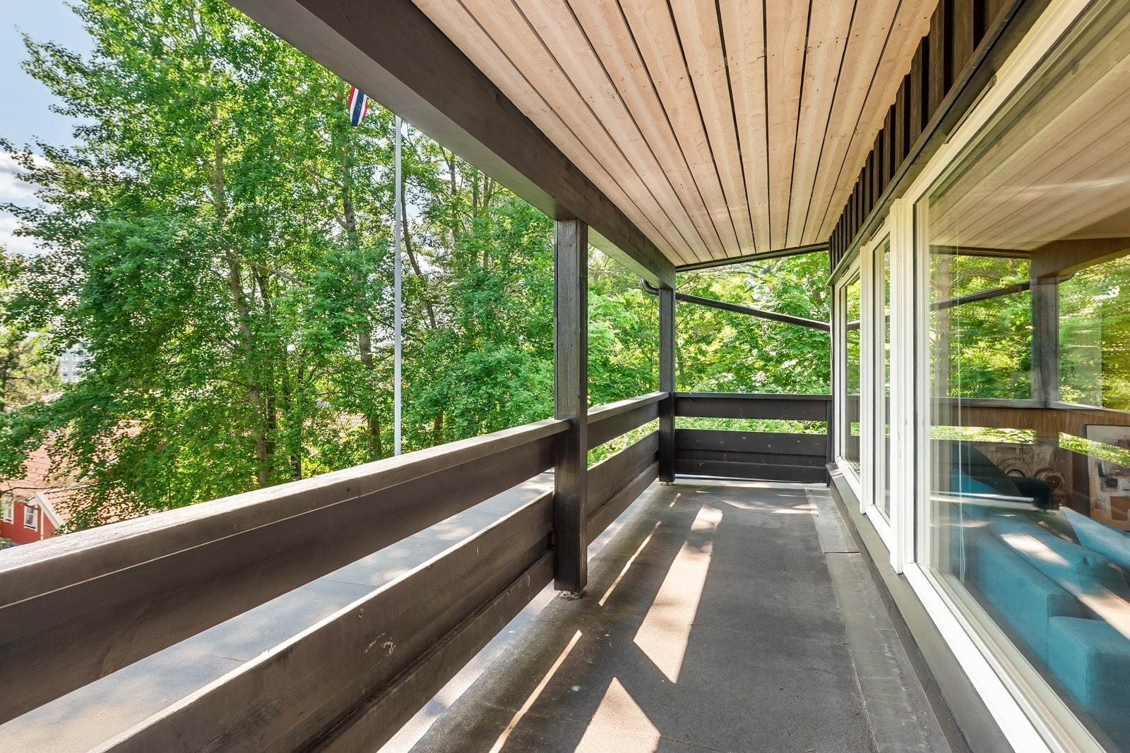 Overbygget balkong med utsikt mot frodige trær og god plass til utemøbler. Galleribilde