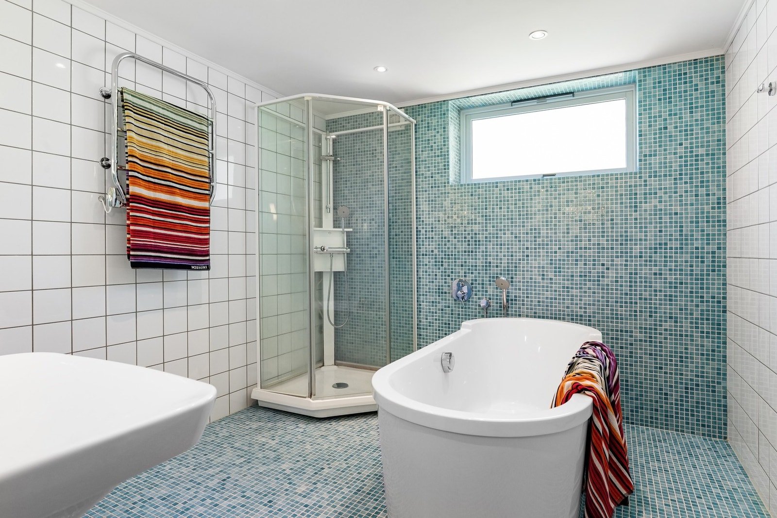 Badet har fliser på vegger og gulv, dusjkabinett, badekar designet av Philippe Starck. Lys og luftig atmosfære. Galleribilde