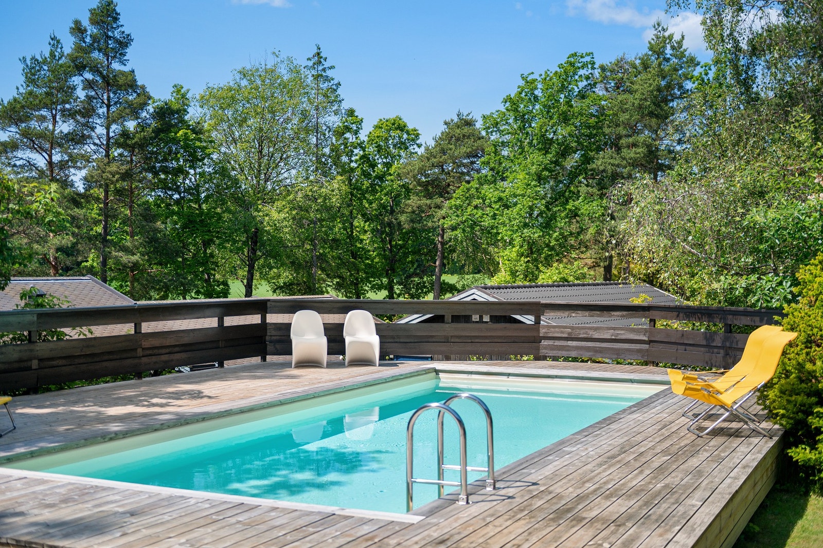 Utendørs svømmebasseng på terrasse med tredekke og utsikt mot grøntområde. Galleribilde