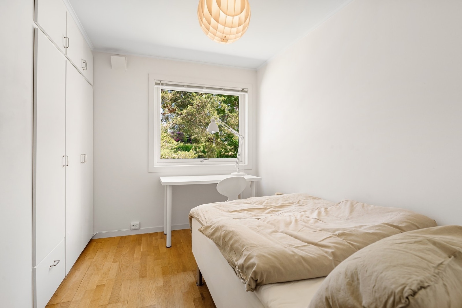 Lyst soverom med hvite vegger, stort vindu og innebygd garderobeskap. Galleribilde