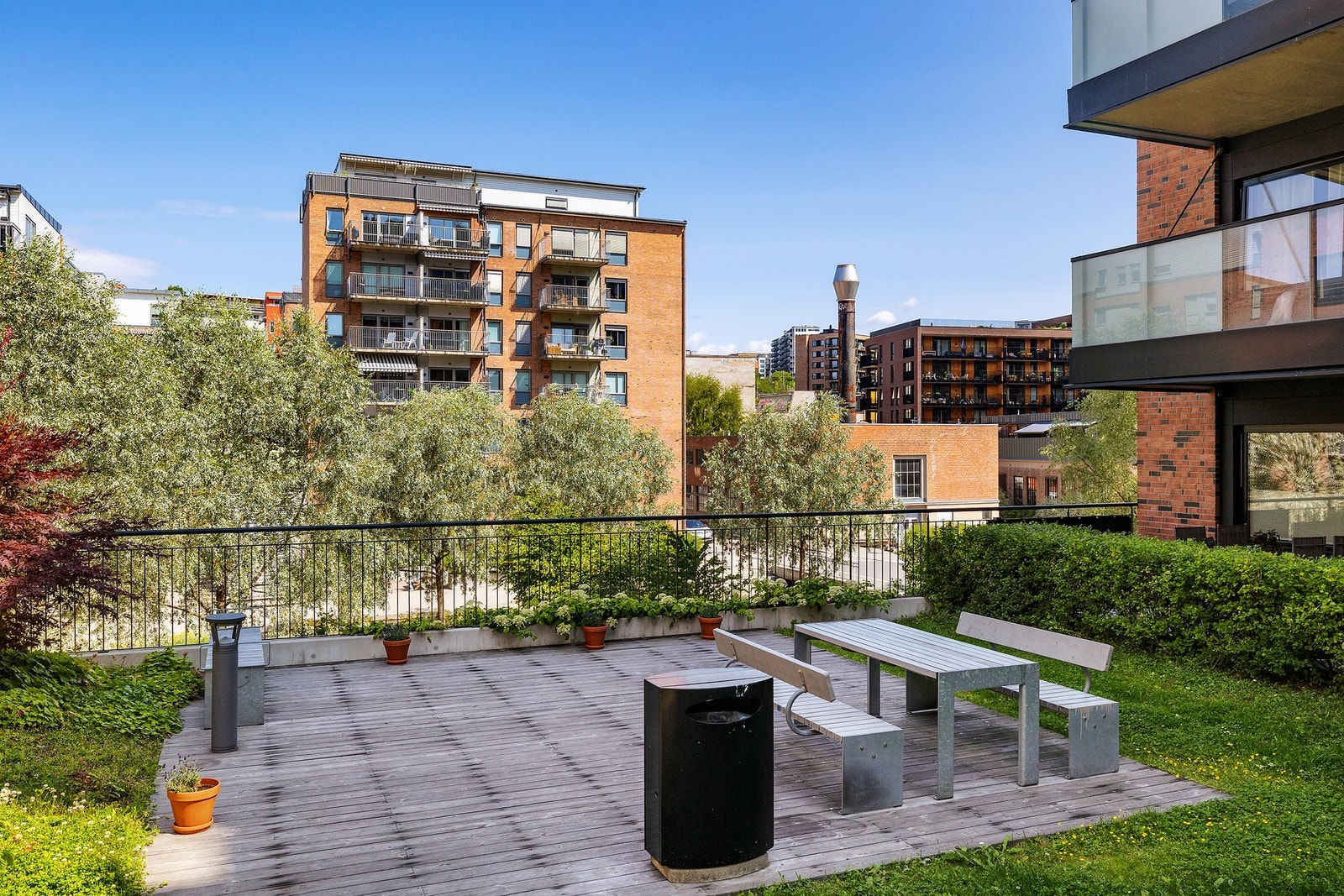 Pent opparbeidet fellesområde i borettslaget med beplantning og sittegruppe. Galleribilde