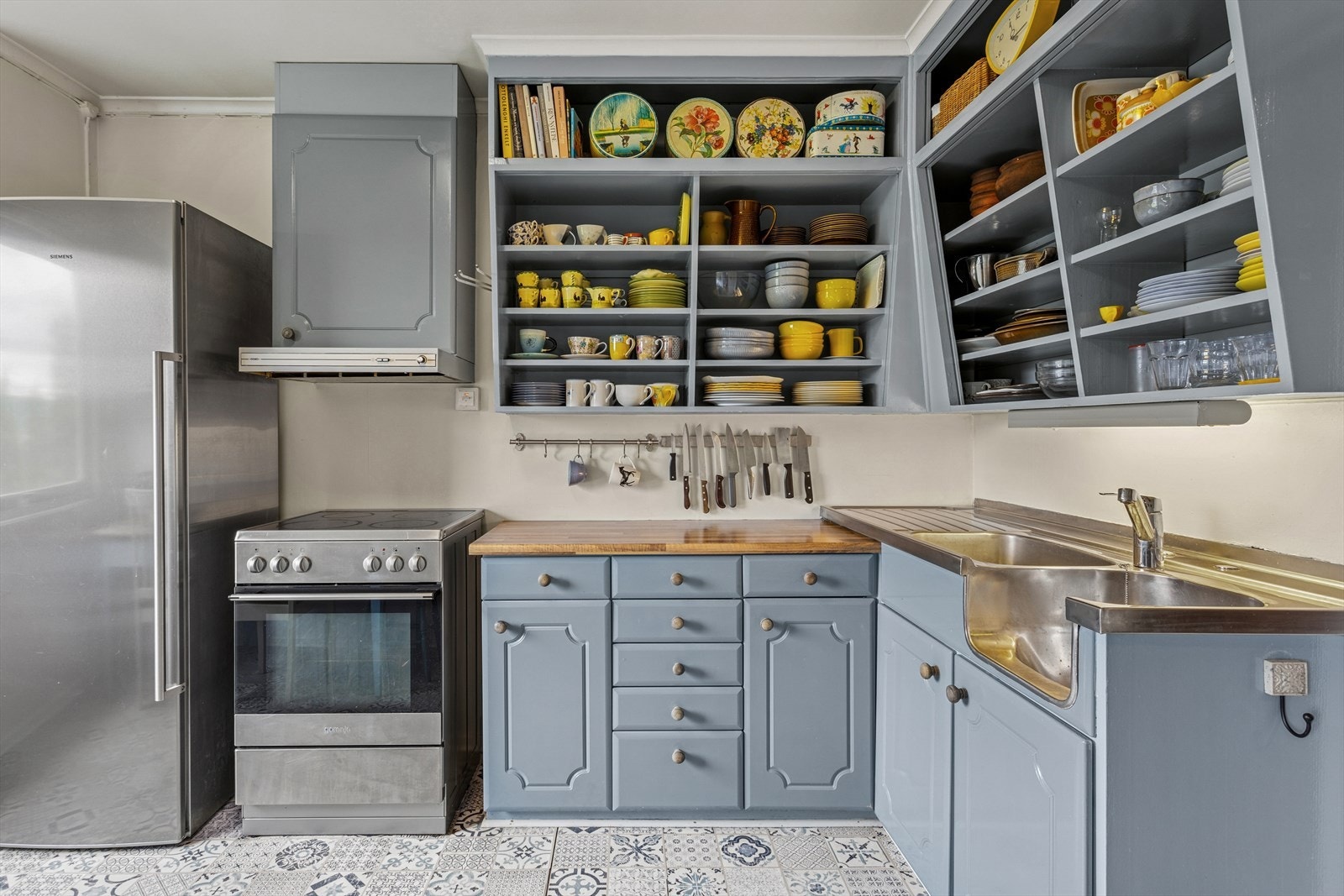 Kjøkkeninnredningen er i heltre med malte, profilerte fronter og delvis heldekkende beslag og delvis laminert benkeplate med dobbel kjøkkenkum. Galleribilde