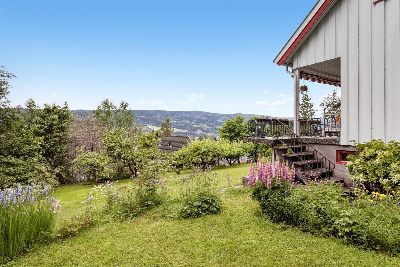 Det er flere flate partier med plen, omkranset av prydbusker og blomsterbed. Galleribilde