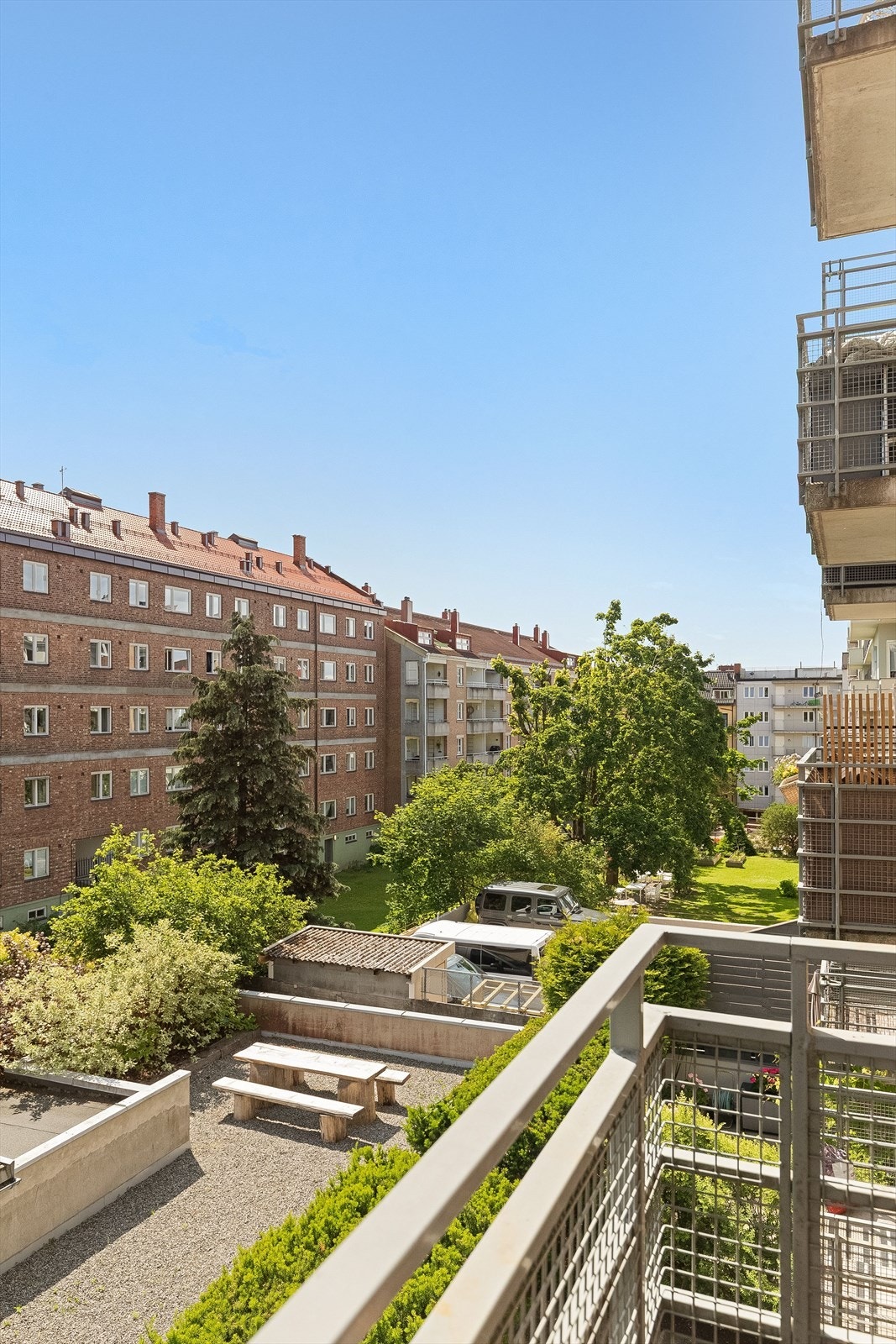 Felles uteområde med sitteplasser og frodige grøntarealer nedenfor balkongen. Galleribilde