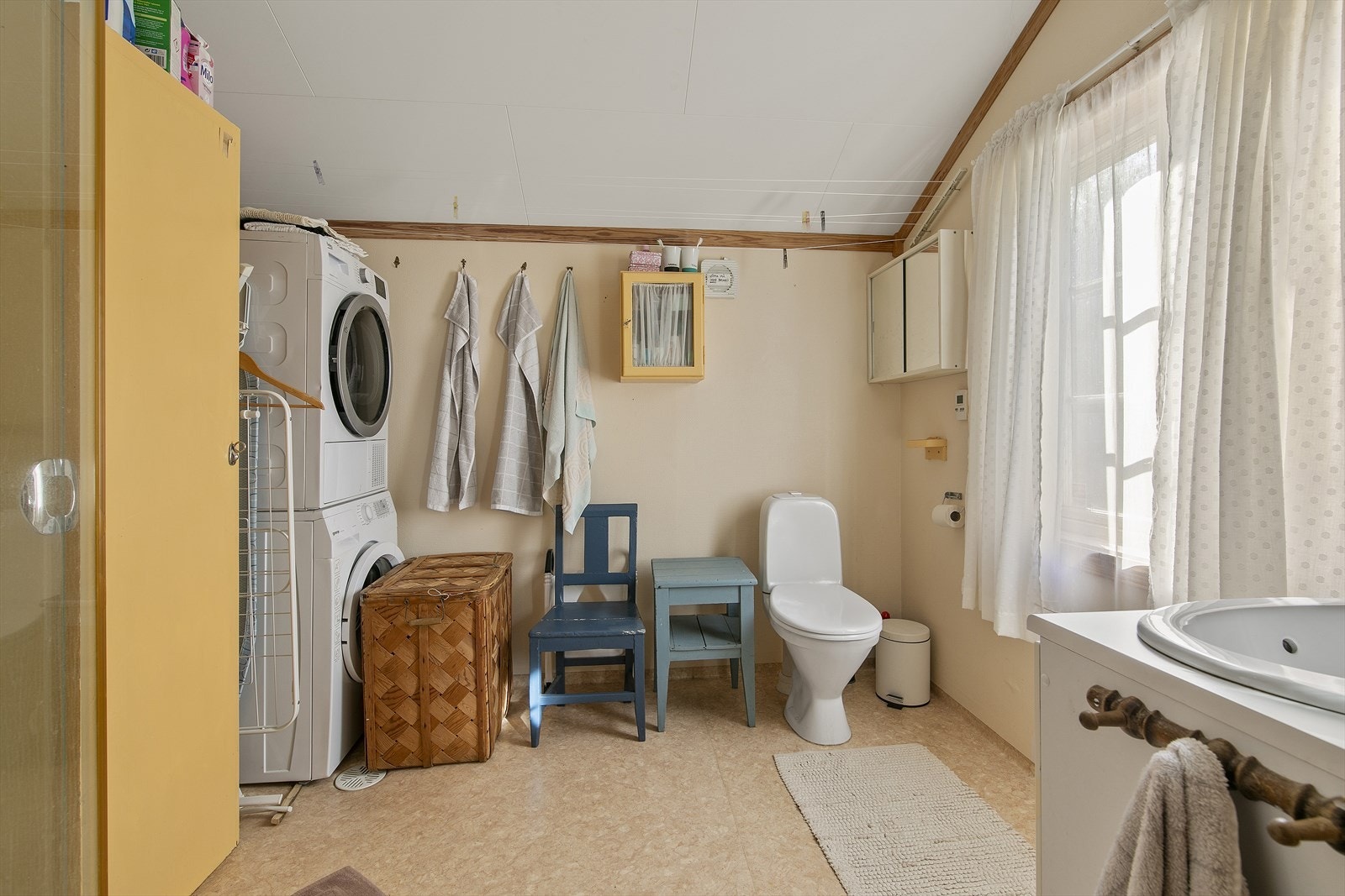 Badet er lyst og inneholder servant med underskap, toalett og opplegg til vaskemaskin og tørketrommel. Galleribilde